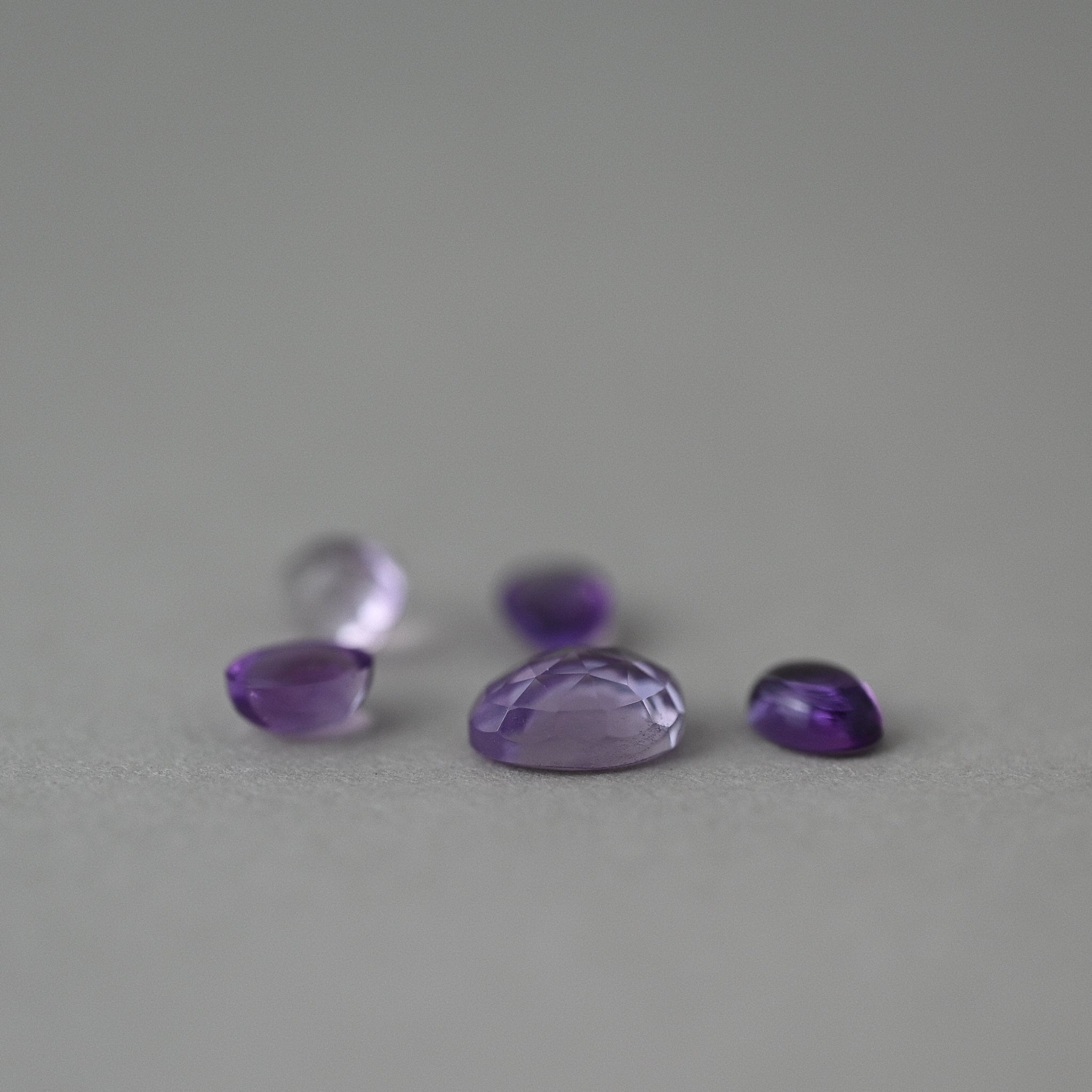 loose amethyst gemstones on grey paper