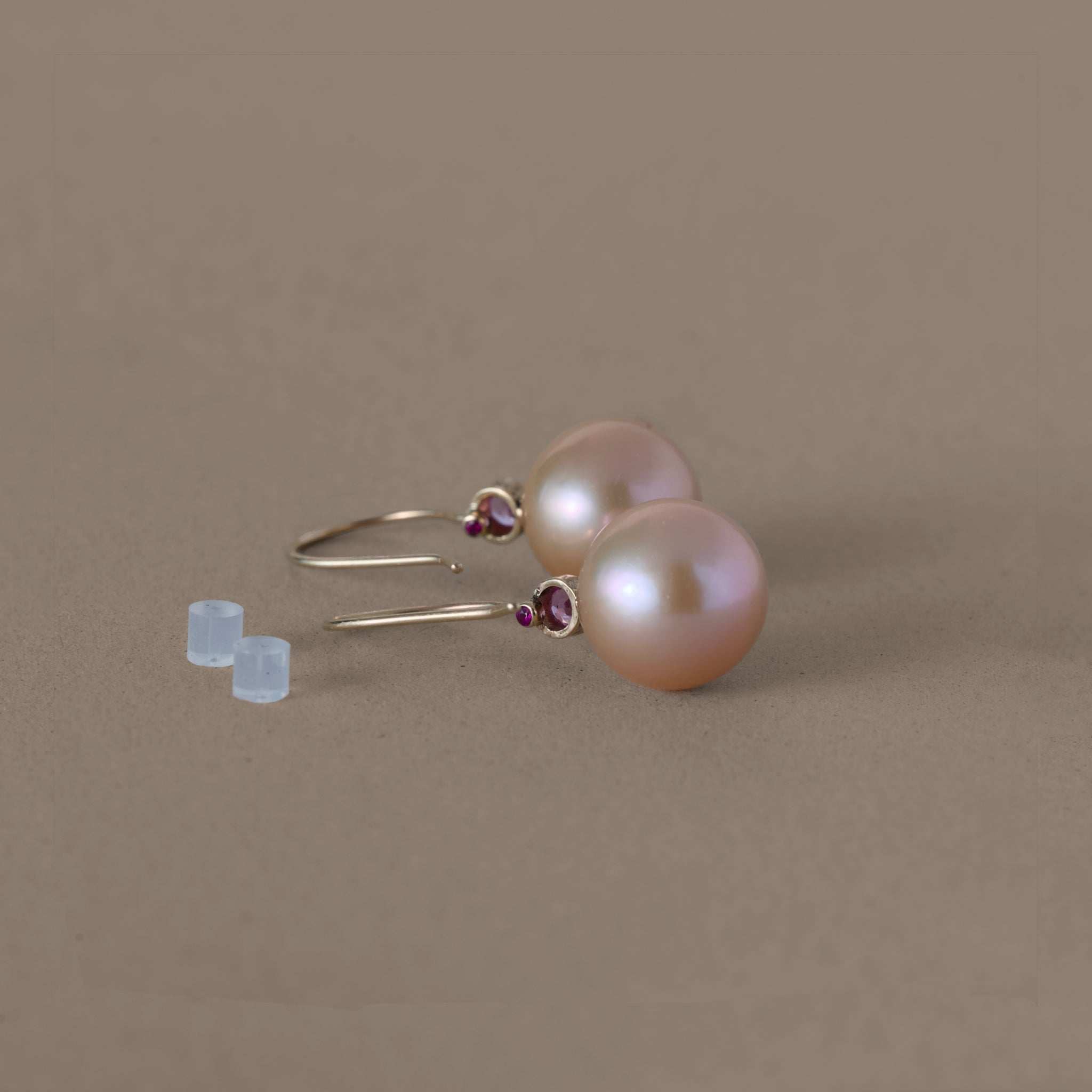 Golden rose freshwater pearl earrings with pink sapphire accents on a neutral background