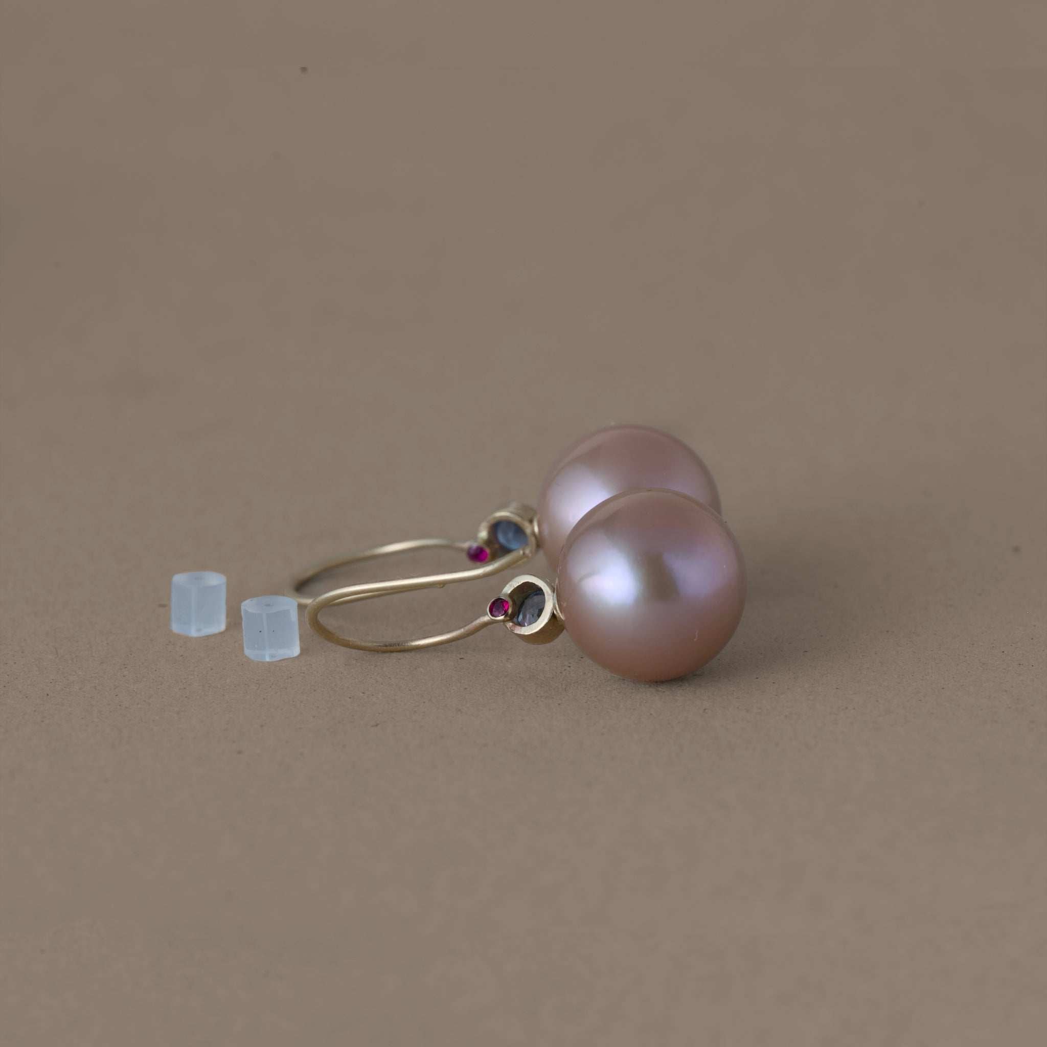 Latte rose freshwater pearl earrings with blue sapphire and gold setting on brown background