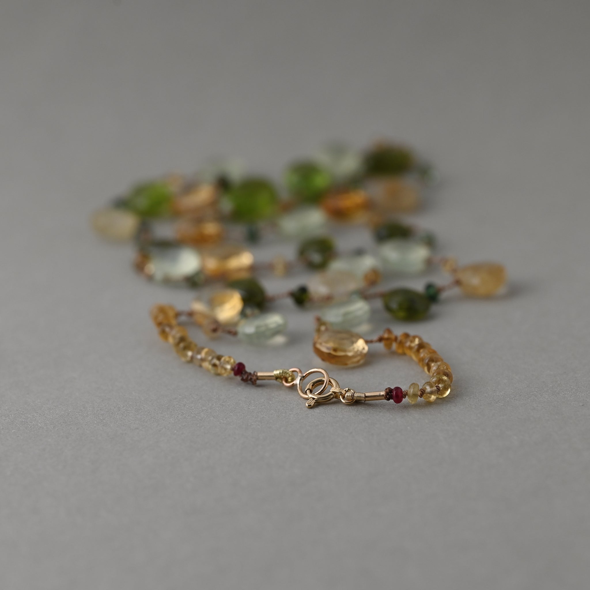 The clasp detail of Lido silk necklace knotted with peridot, citrine, prehnite, quartz gemstones and finished with a 14ct gold clasp