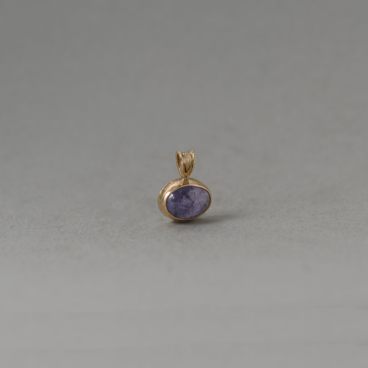 Close-up of Uno Tanzanite pendant necklace with violet hues set in solid 14ct gold, symbolizing tranquility and spirit