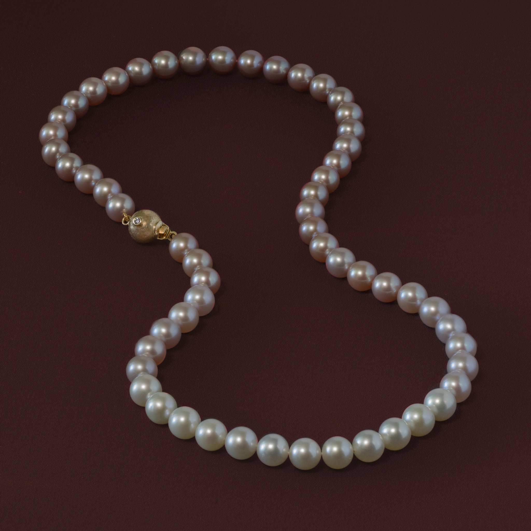 Colour-fade pink pearl necklace with gold clasp, adorned with ruby and diamond.