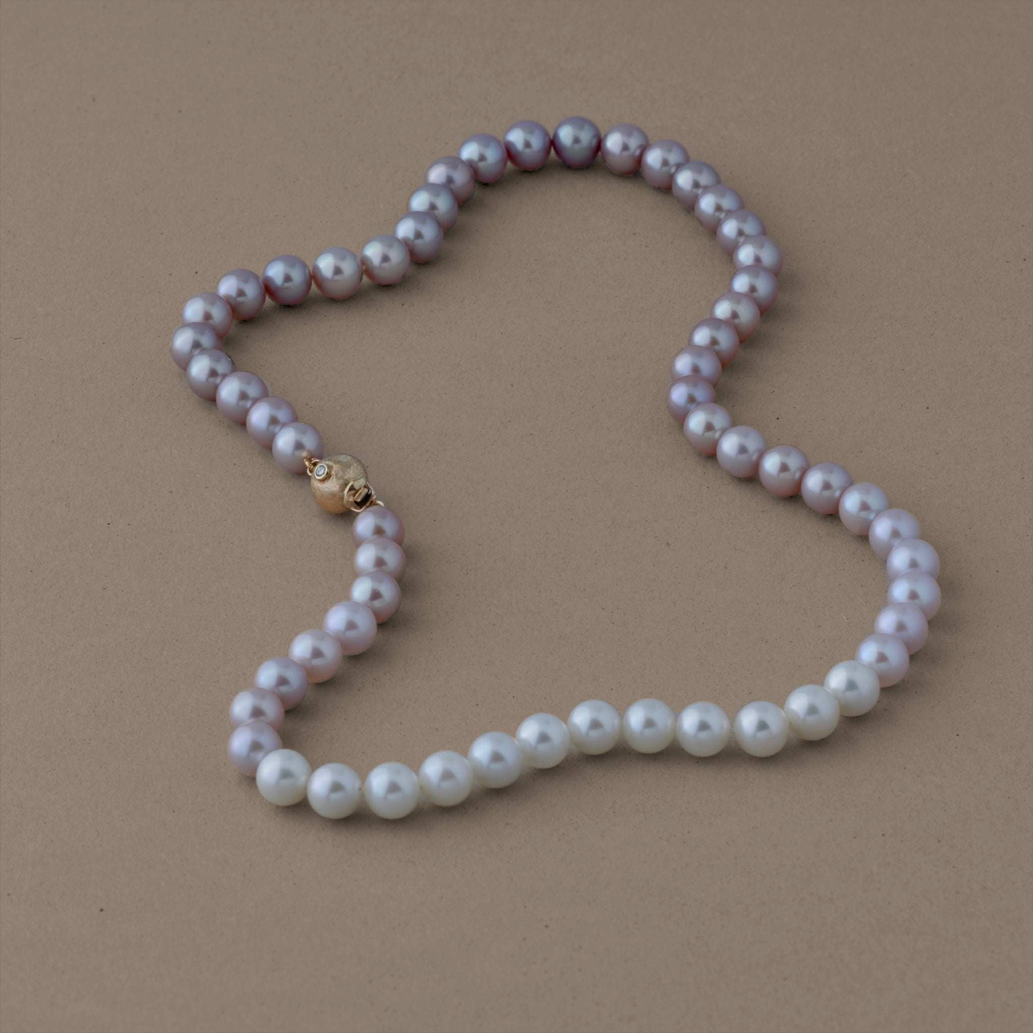 Colour-fade pink pearl necklace with gold clasp, accented by ruby and diamond.