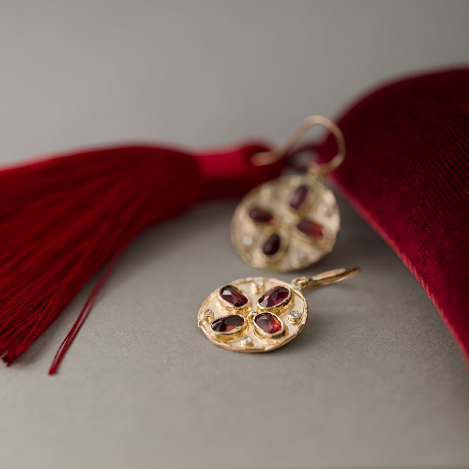 Florin garnet earrings in solid 14ct gold with rose-cut diamonds beside red Lunar tassel.