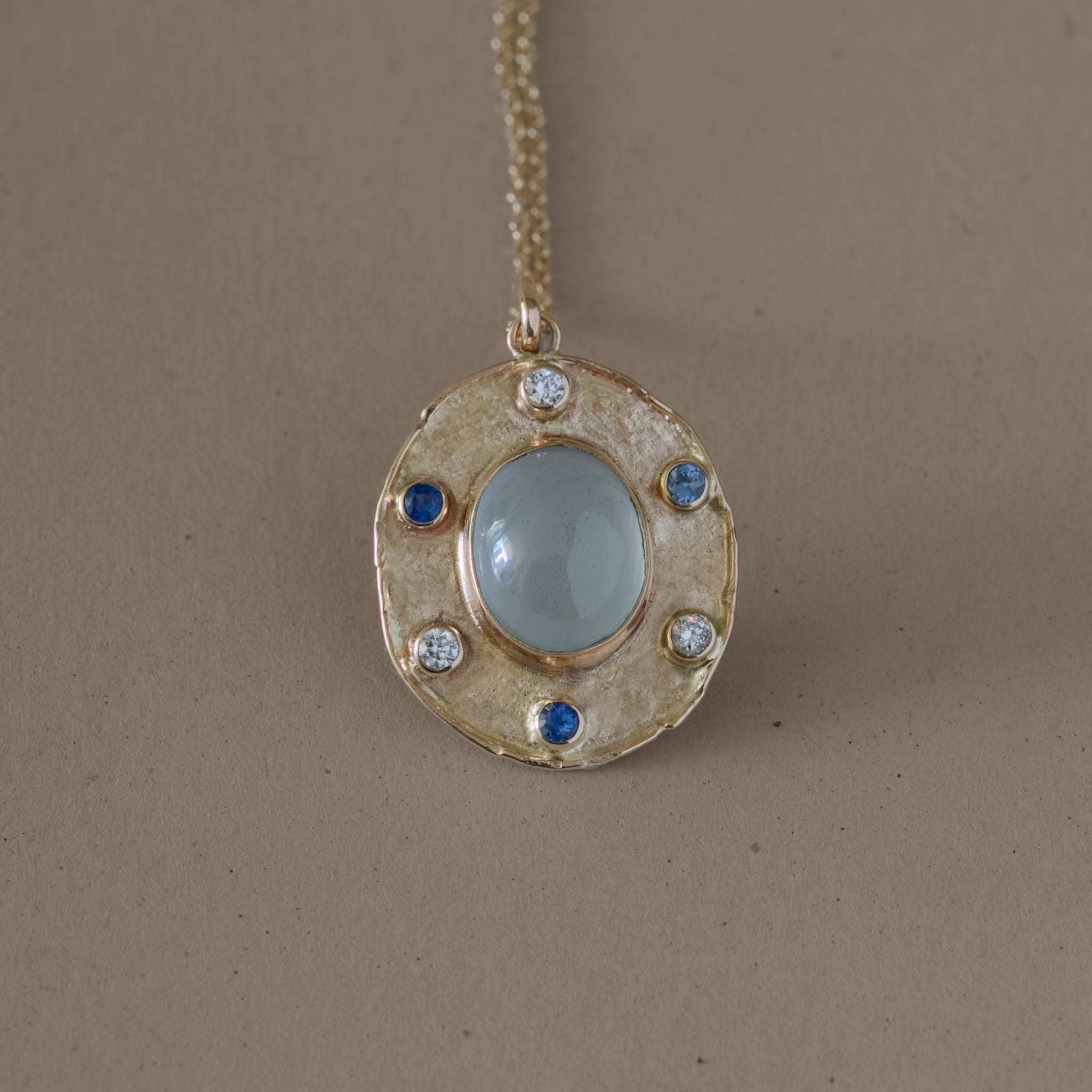 Aquamarine pendant with diamonds and sapphires set in a gold medallion.