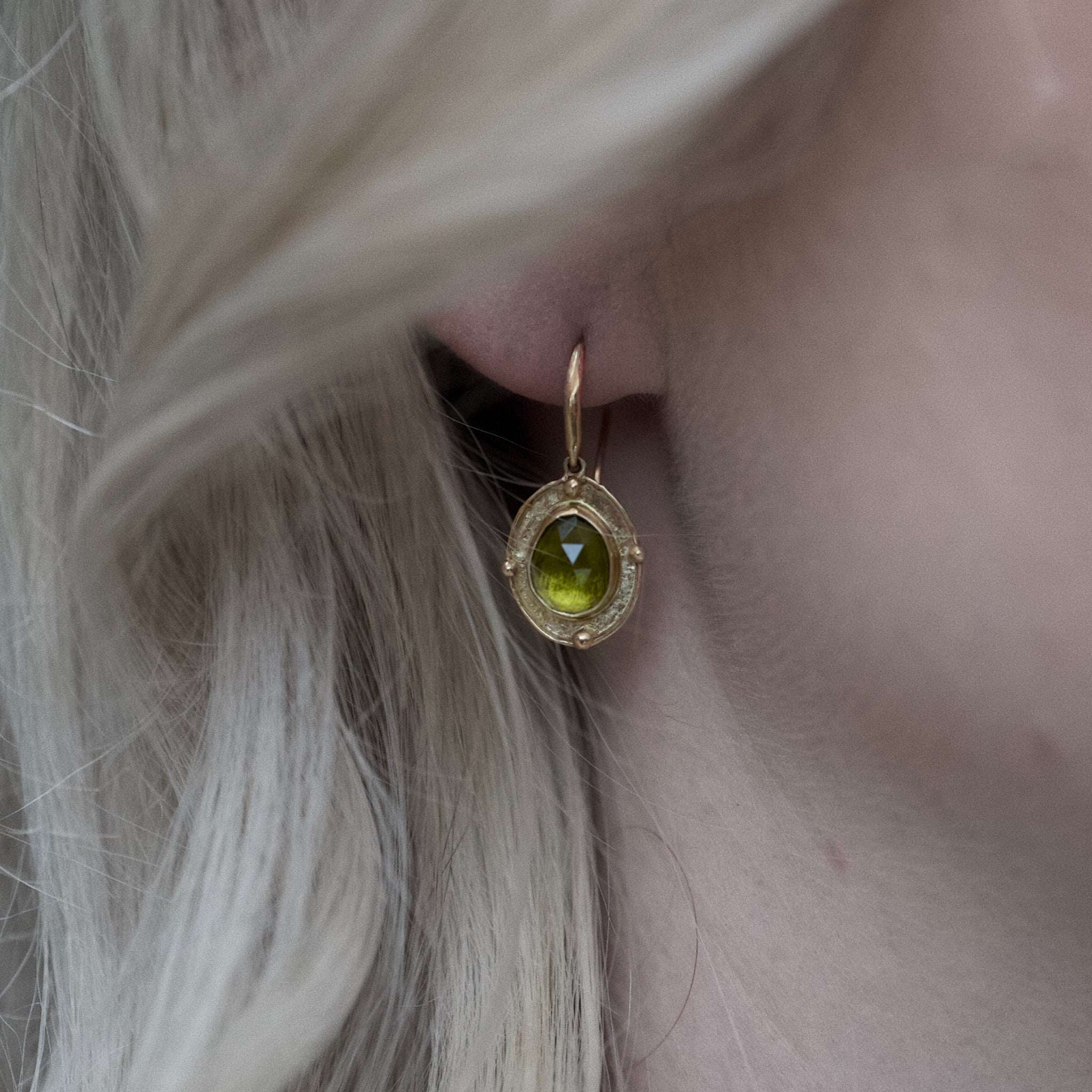 Florin peridot earrings with hammered olive gold medallions and deep lime green peridot gemstones worn on ear