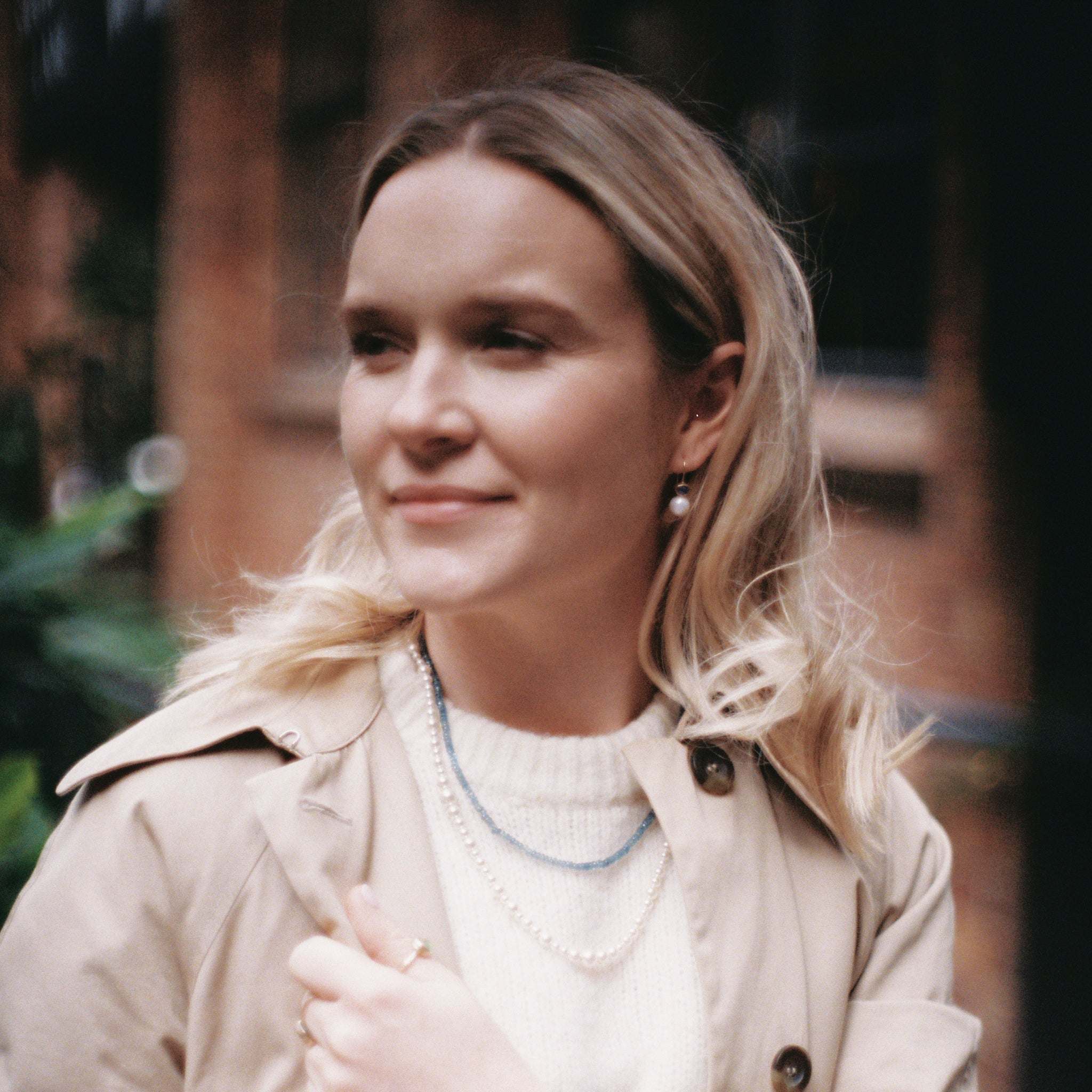 Woman wearing elegant Ceylon blue sapphire pearl earrings with gold setting