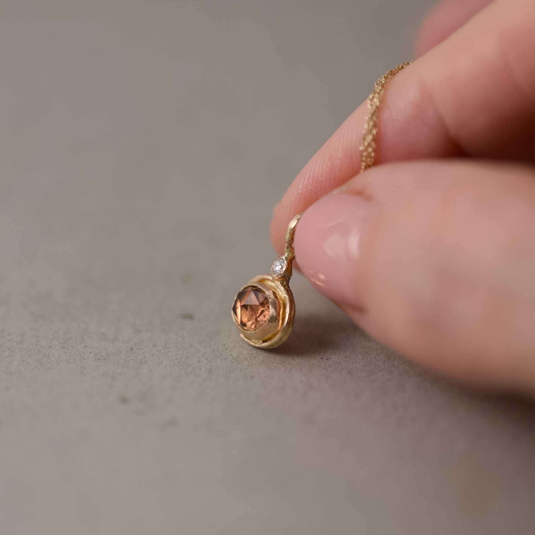 imperial topaz pendant with chain held in fingers