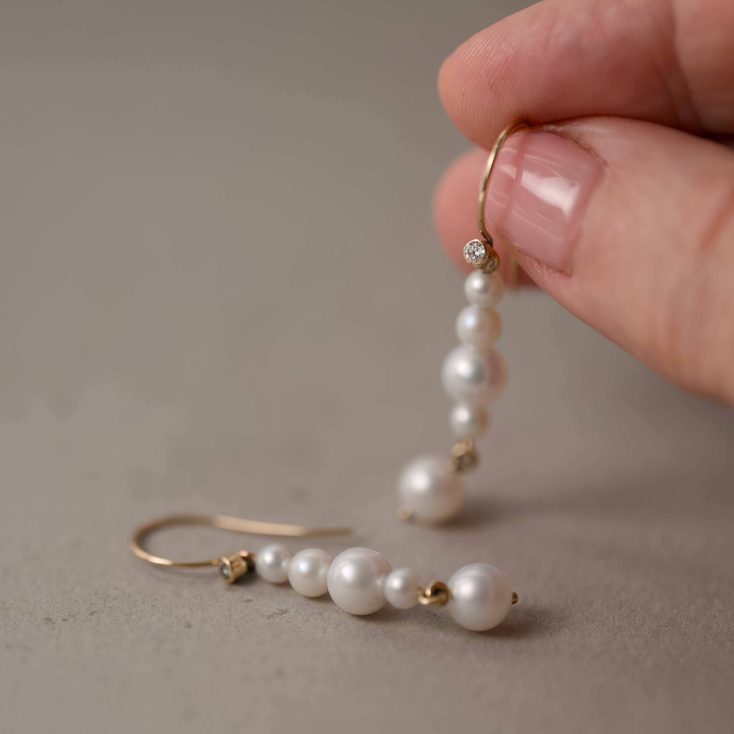 ondina pearl drop earrings held in fingers