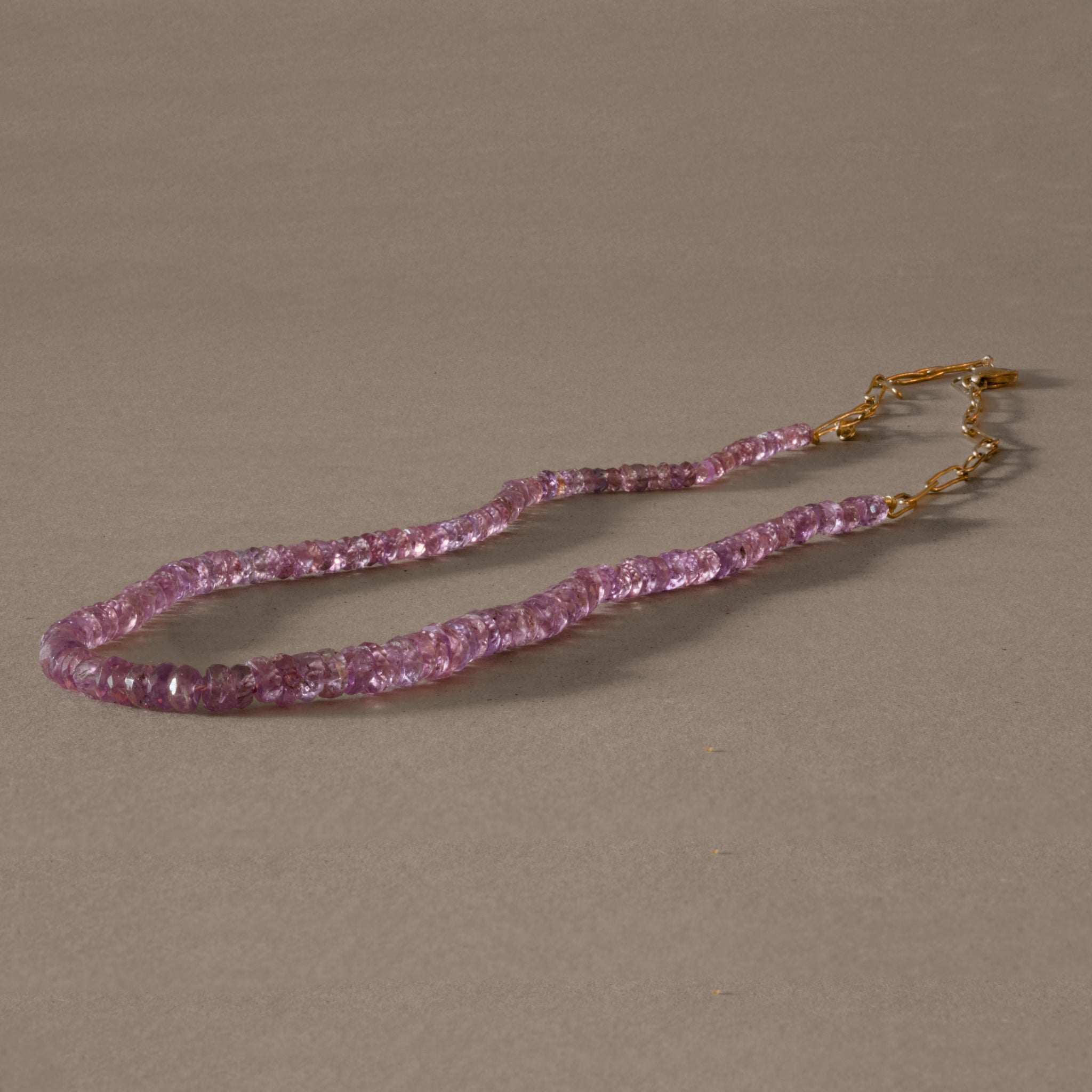 Pink sapphire necklace with gold chain, elegant gemstone jewelry.