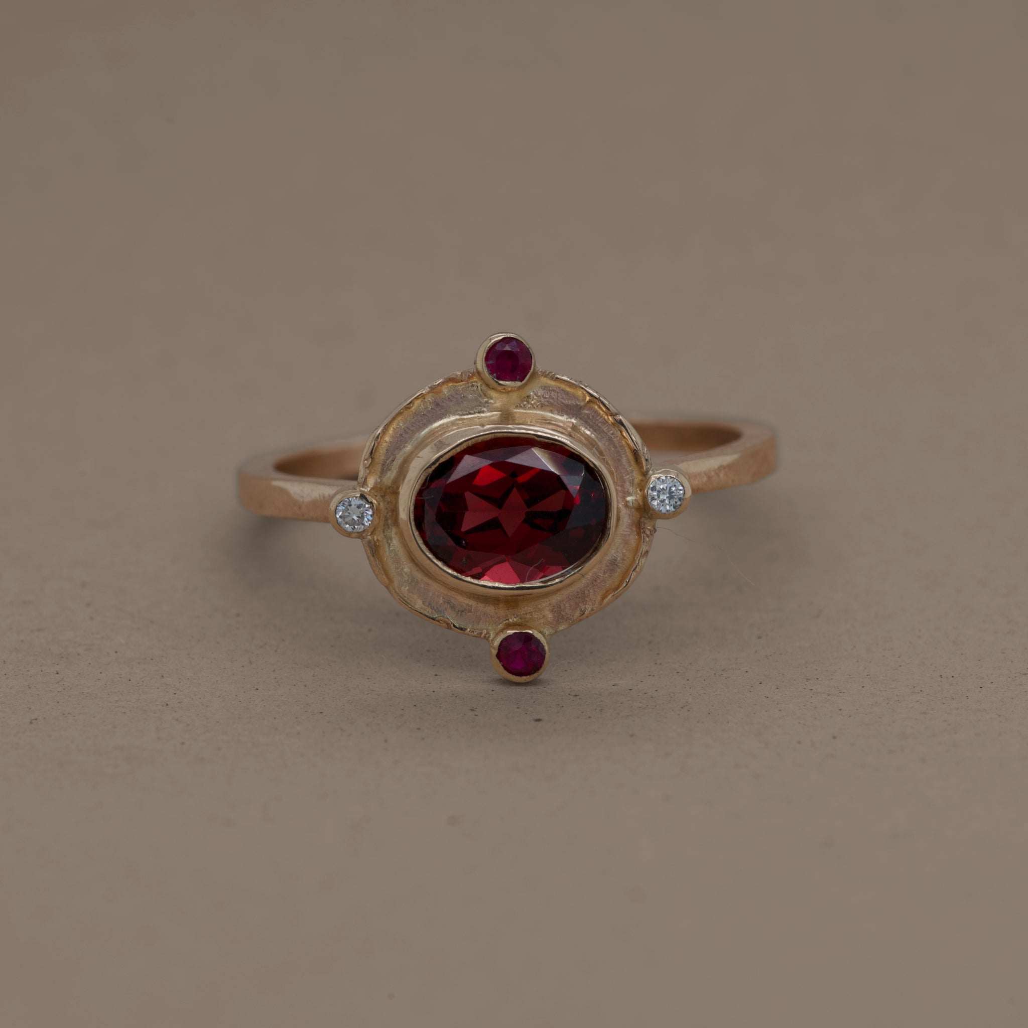 Gold ring with deep red garnet, ruby accents, and diamond details.