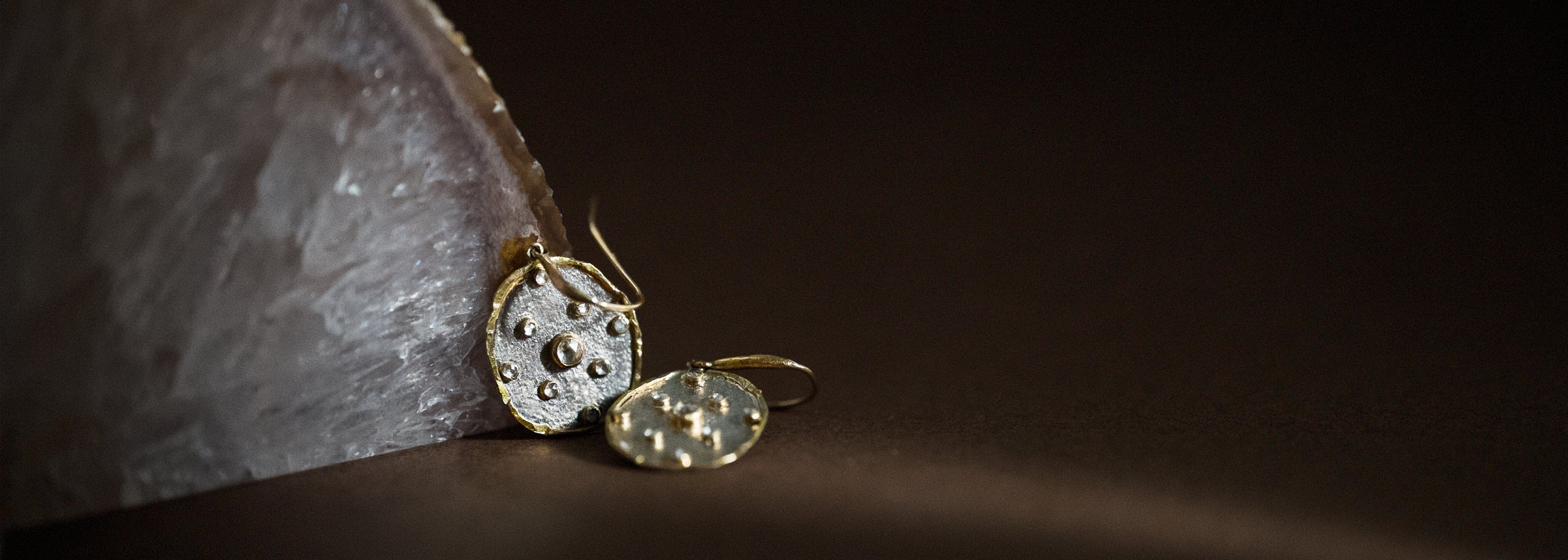 Rose cut diamond Florin earrings in solid gold and platinum against raw stone