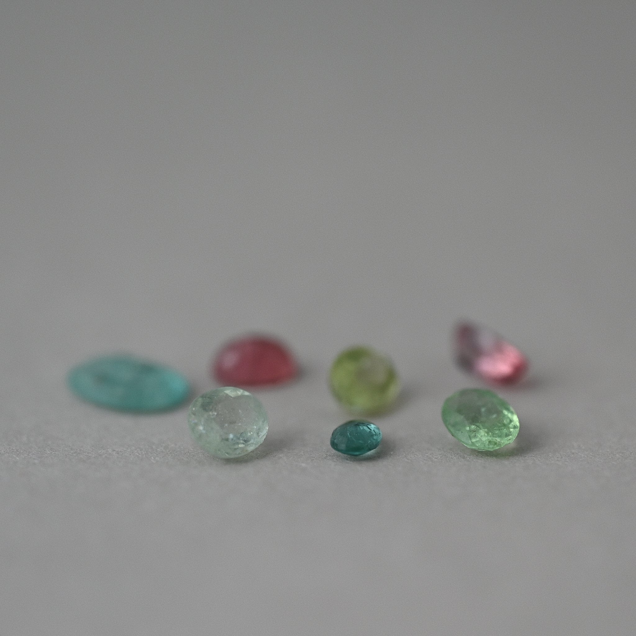 loose tourmaline gemstones on grey paper
