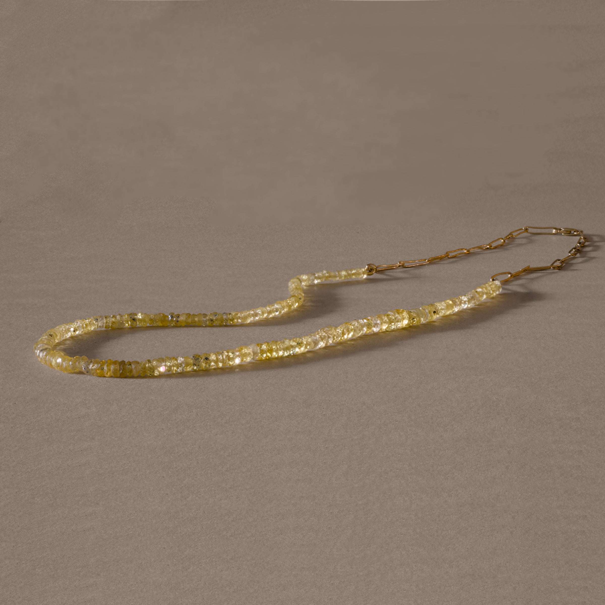 Yellow sapphire necklace with gold links on fine silk, exuding vibrant golden radiance.
