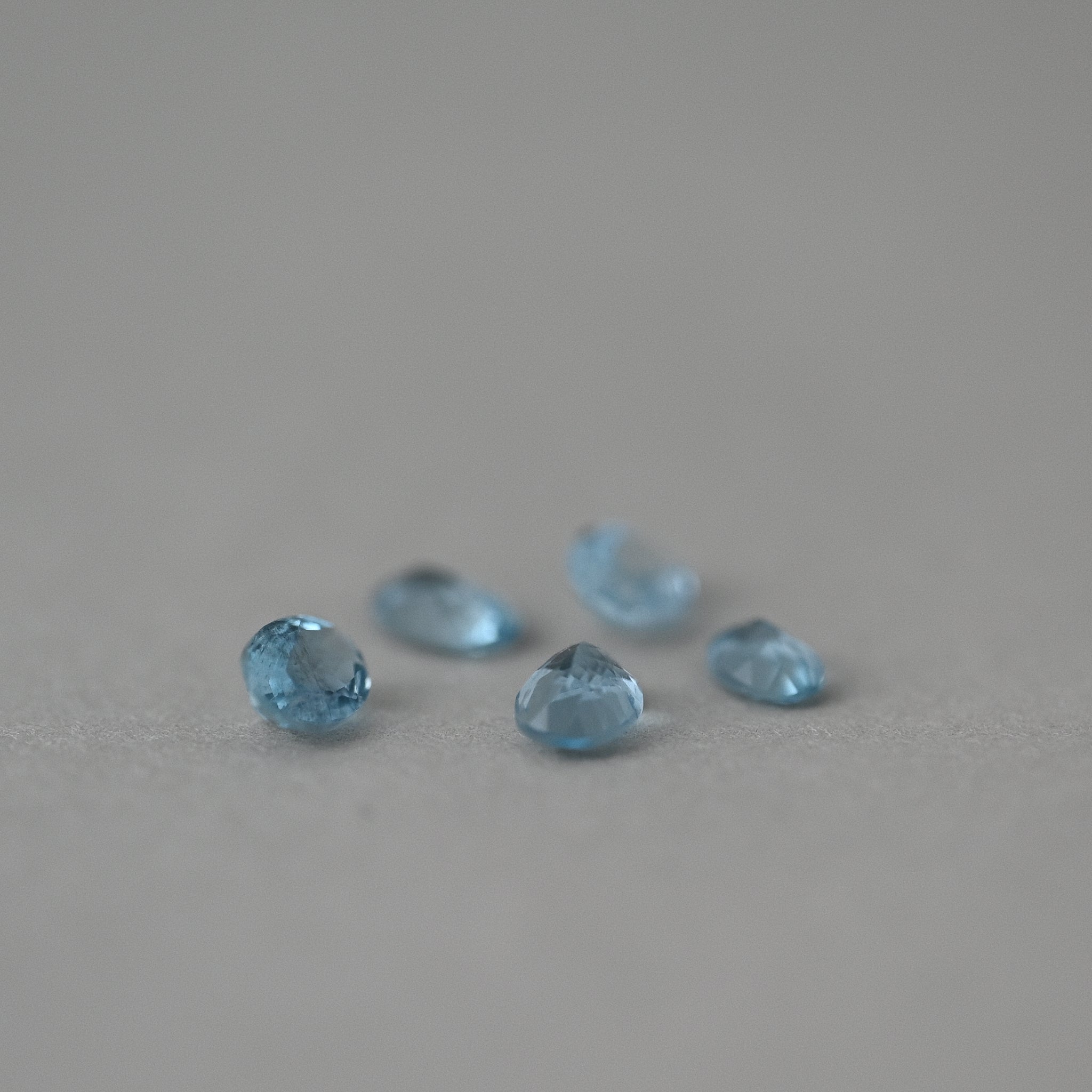 loose aquamarine gemstones on grey paper