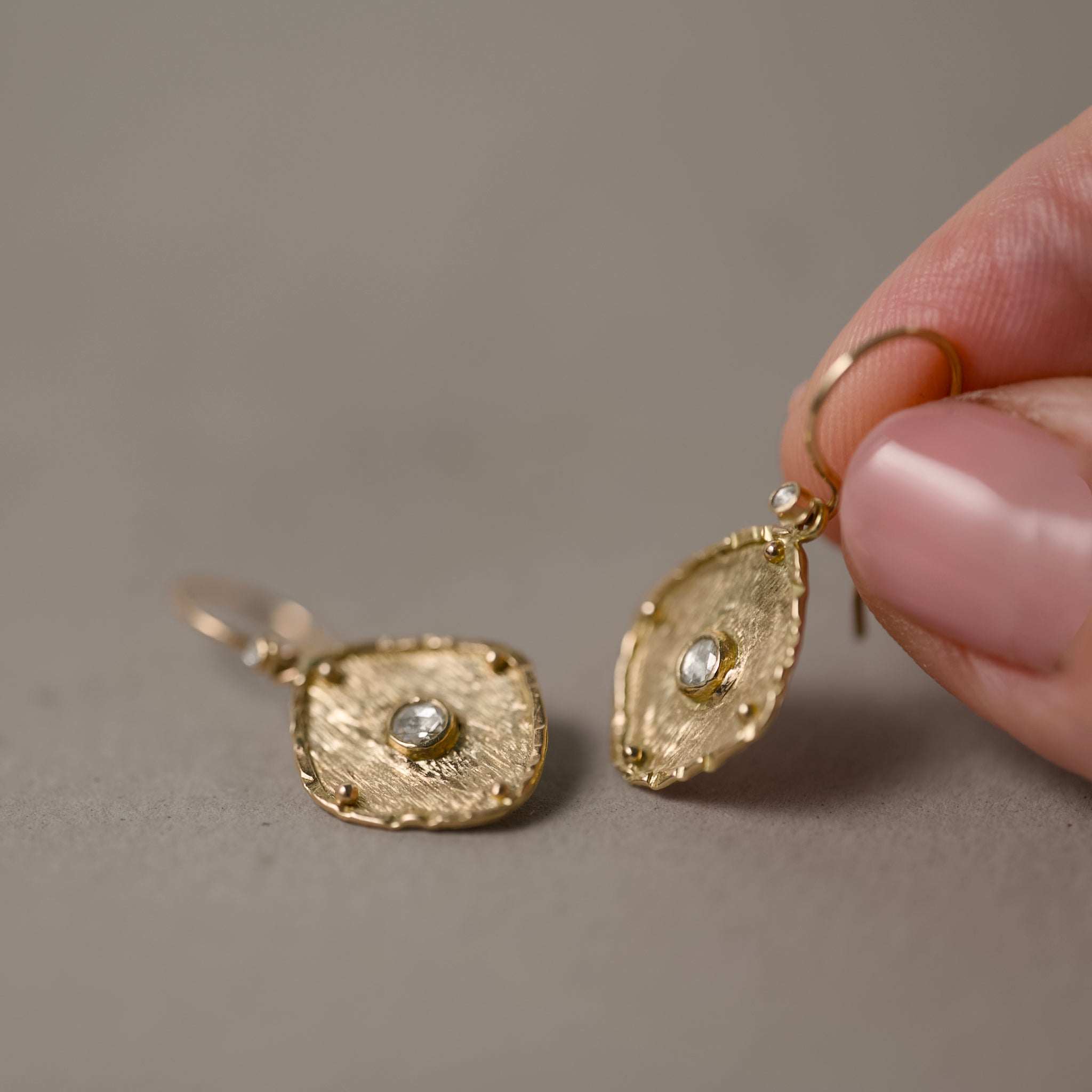 Florin rose cut diamond earrings held in fingers 
