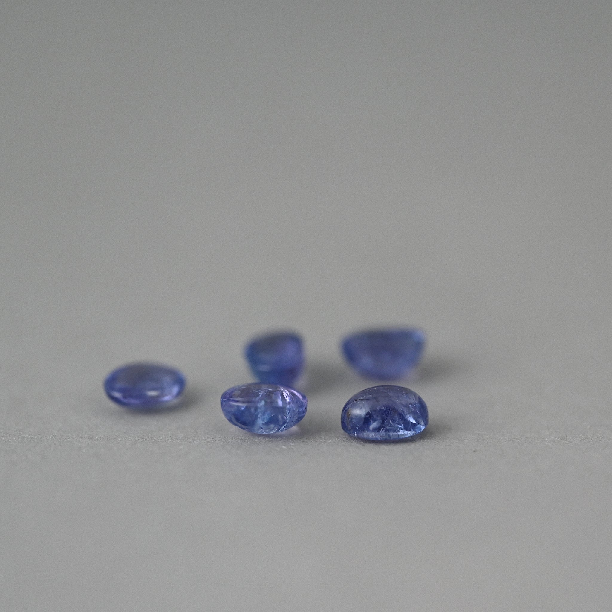 loose tourmaline gemstones on grey paper