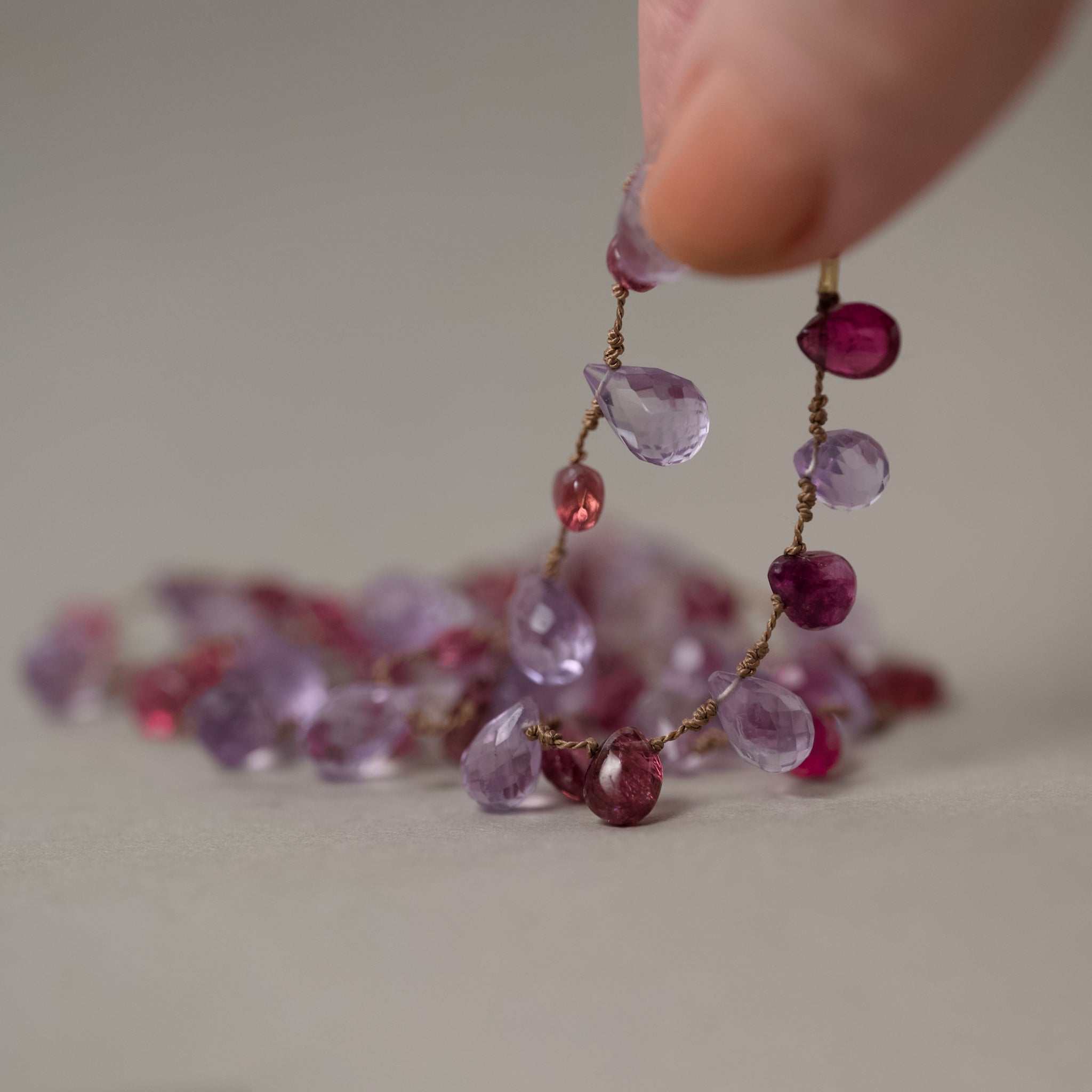 Lido amethyst and garnet 14ct gold silk necklace held by fingers