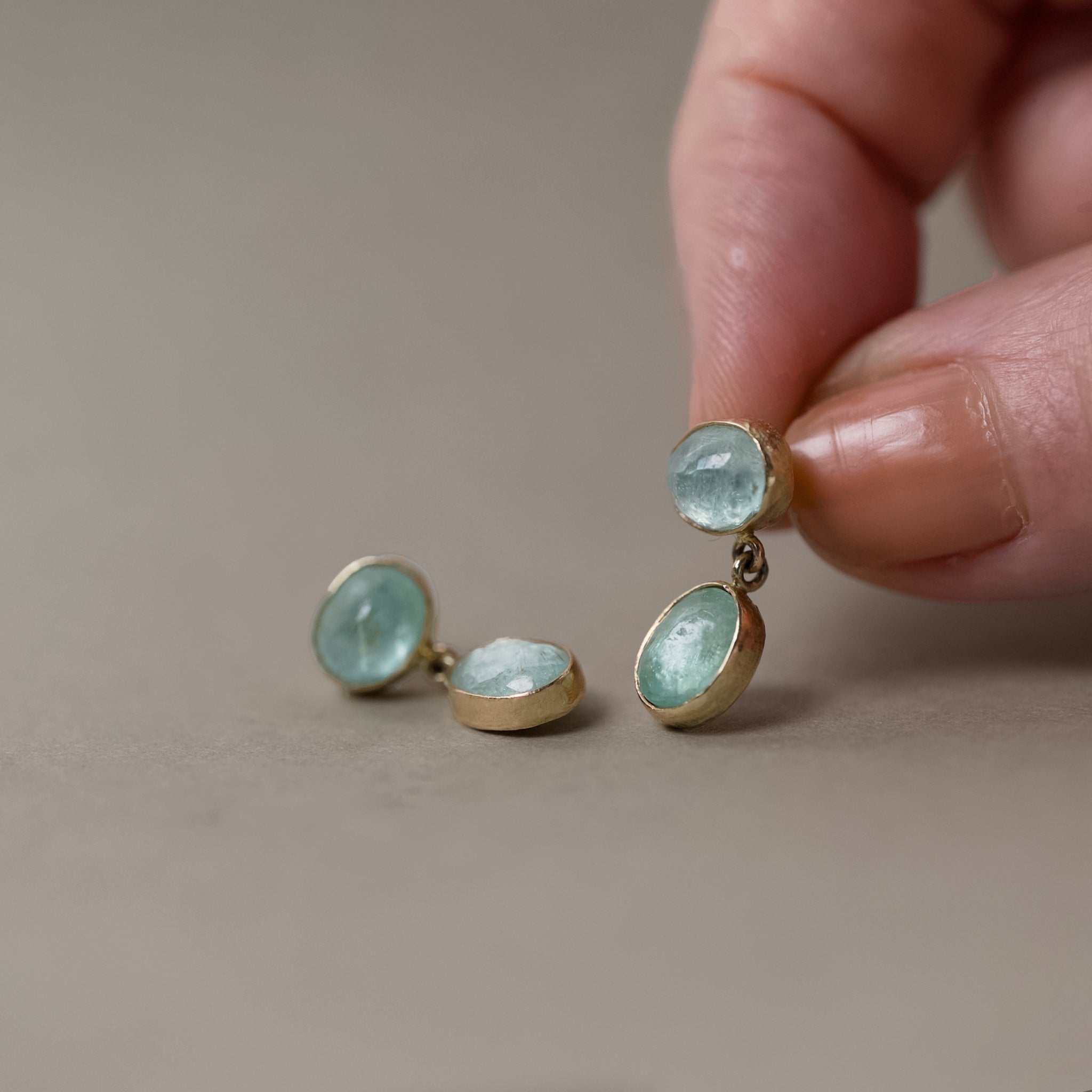 14ct gold earrings with paraiba tourmaline held in fingers 