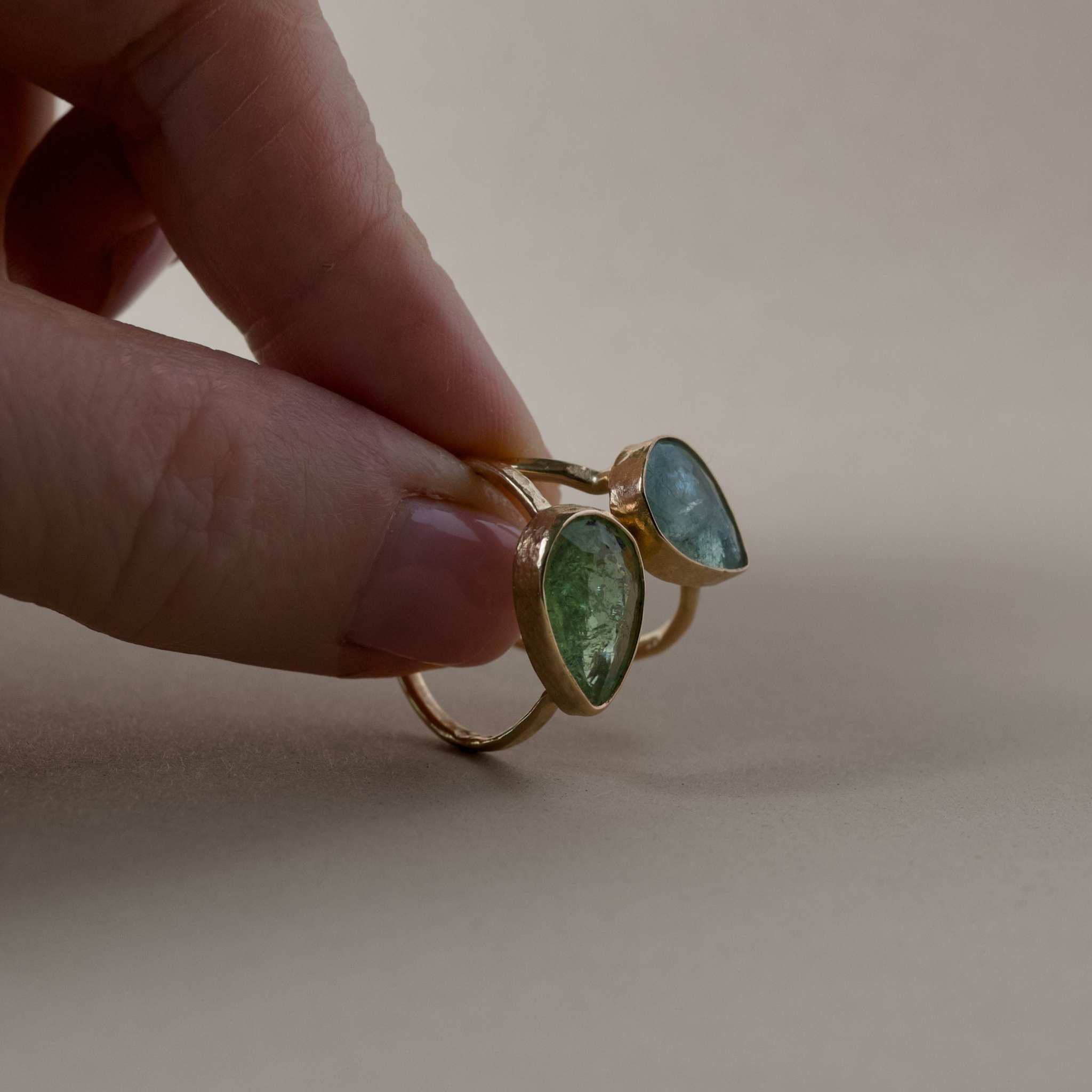 Hand holding a Pero Blue Paraíba Tourmaline Ring with hammered gold band and icy aqua blue gemstone.