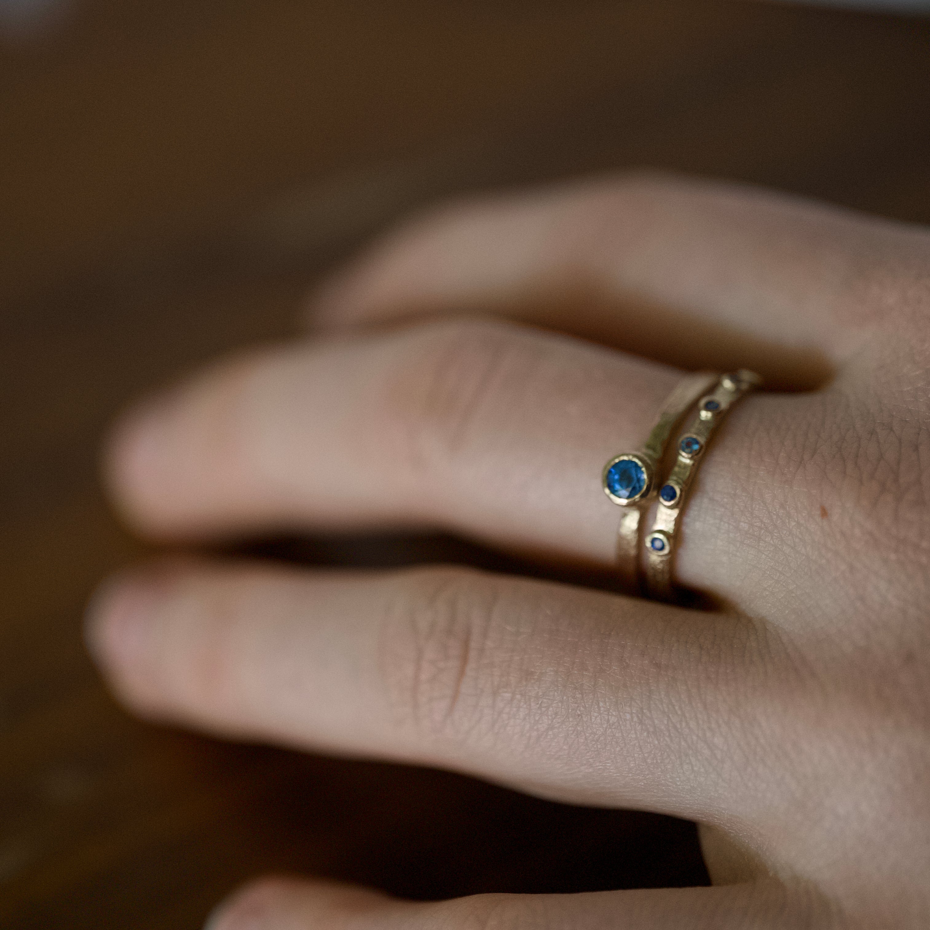 Stellata Sapphire Ring featuring gold band with scattered blue sapphires on finger