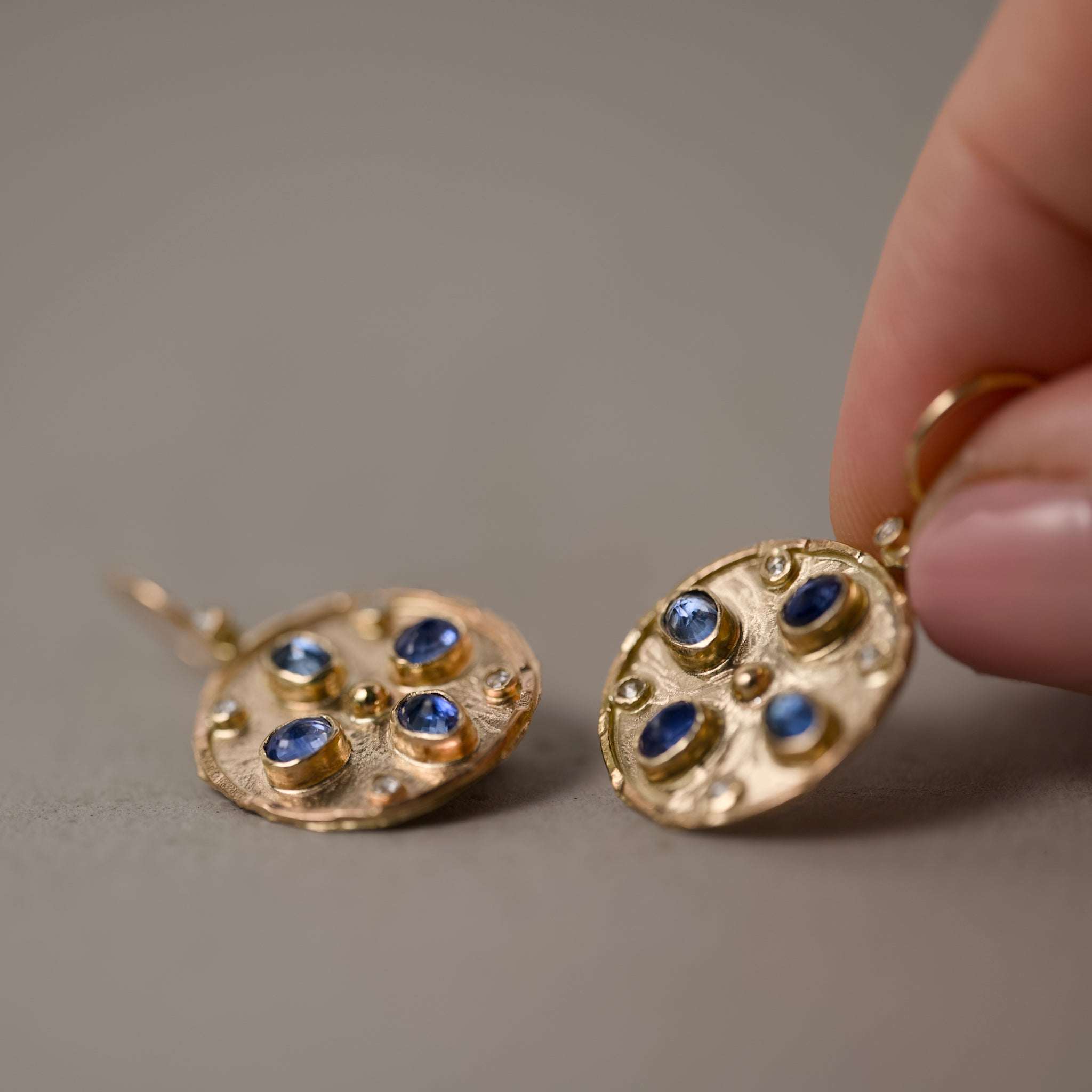 Florin blue sapphire rose cut diamond earrings held I hand