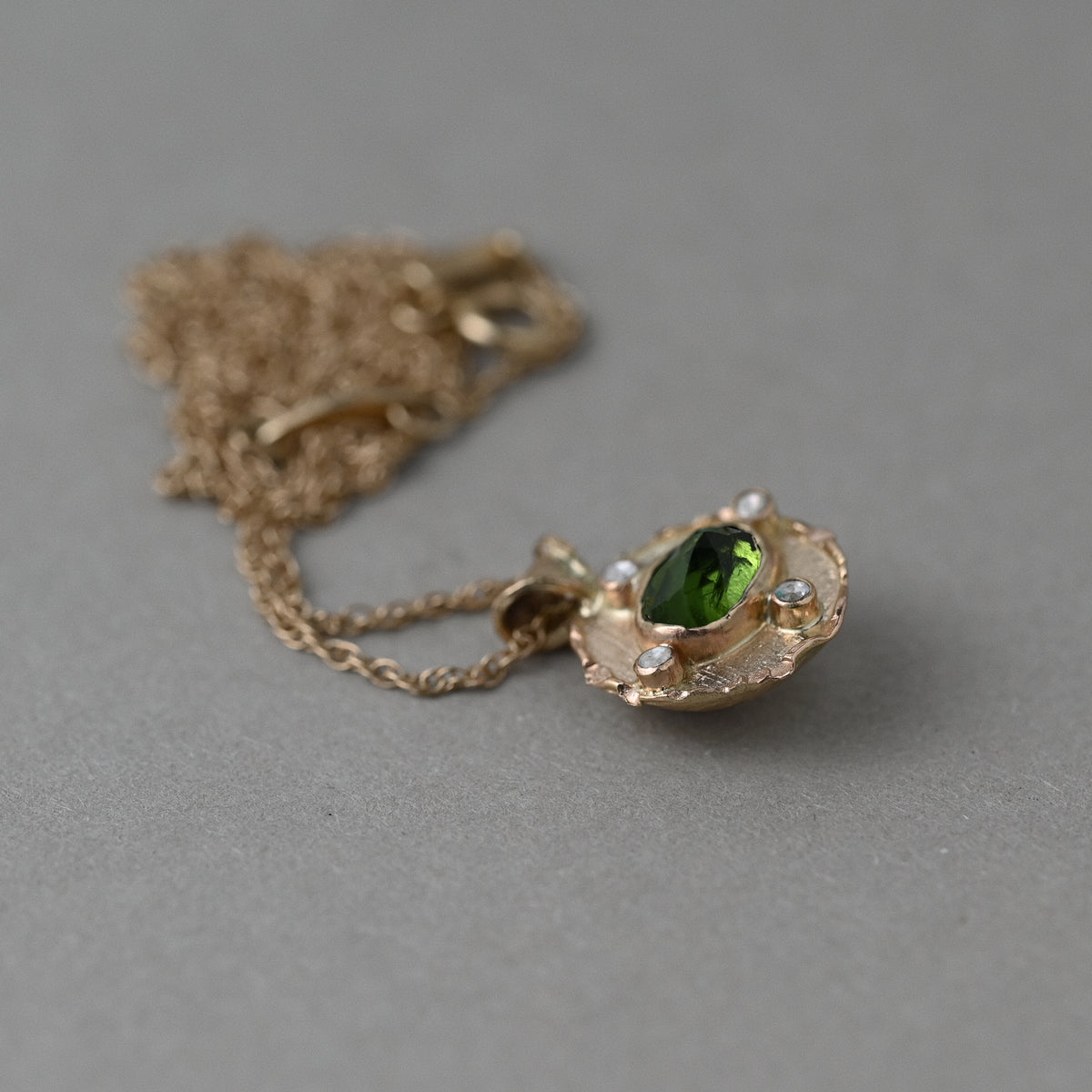 Vermilion Jewellery Florin medallion featuring green tourmalines set in textured 14ct solid gold, photographed from the front.