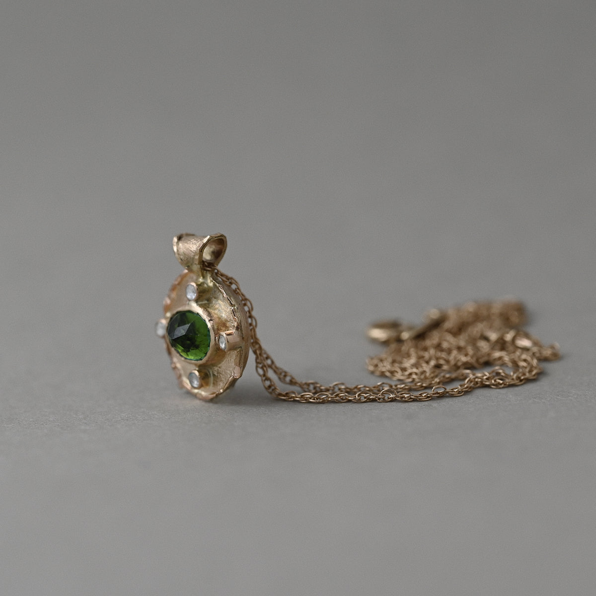 Vermilion Jewellery Florin green tourmaline earrings in textured 14ct solid gold, shown upright to reveal their sculptural design.