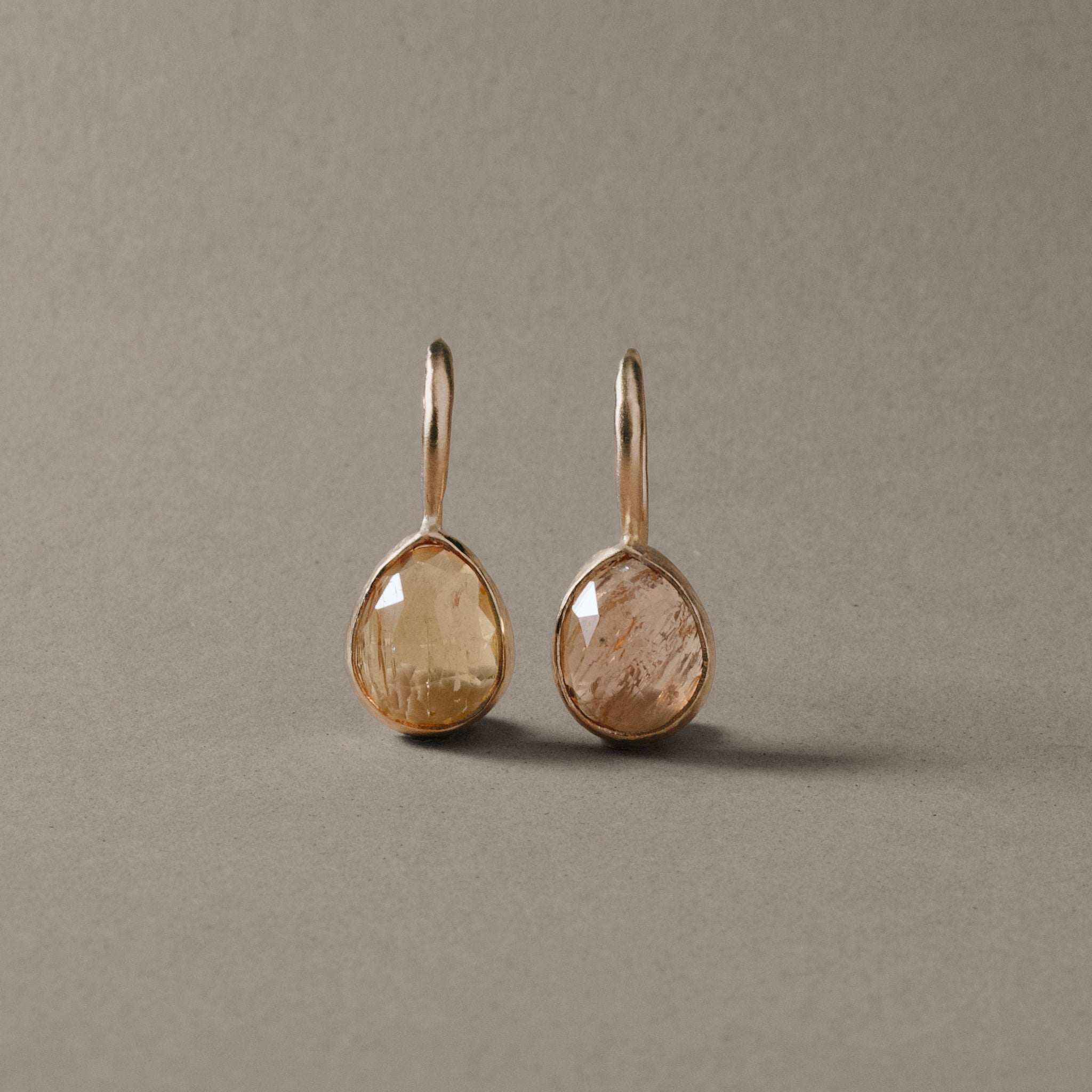 Teardrop Imperial Topaz Earrings in gold settings with peach and gold hues.