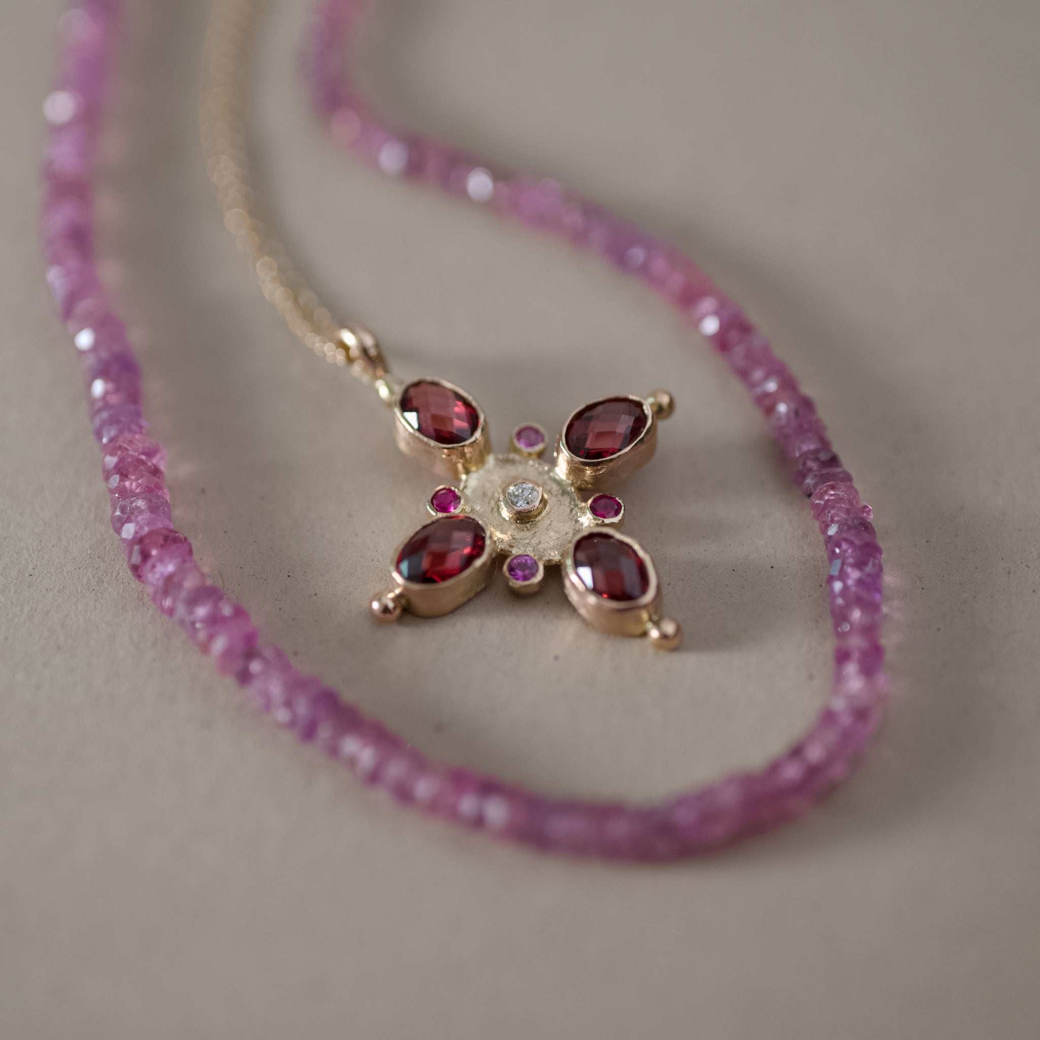 Stella Garnet Sapphire Necklace with pink rhodolite garnets, sapphires, rubies, and a diamond set in 14k gold.