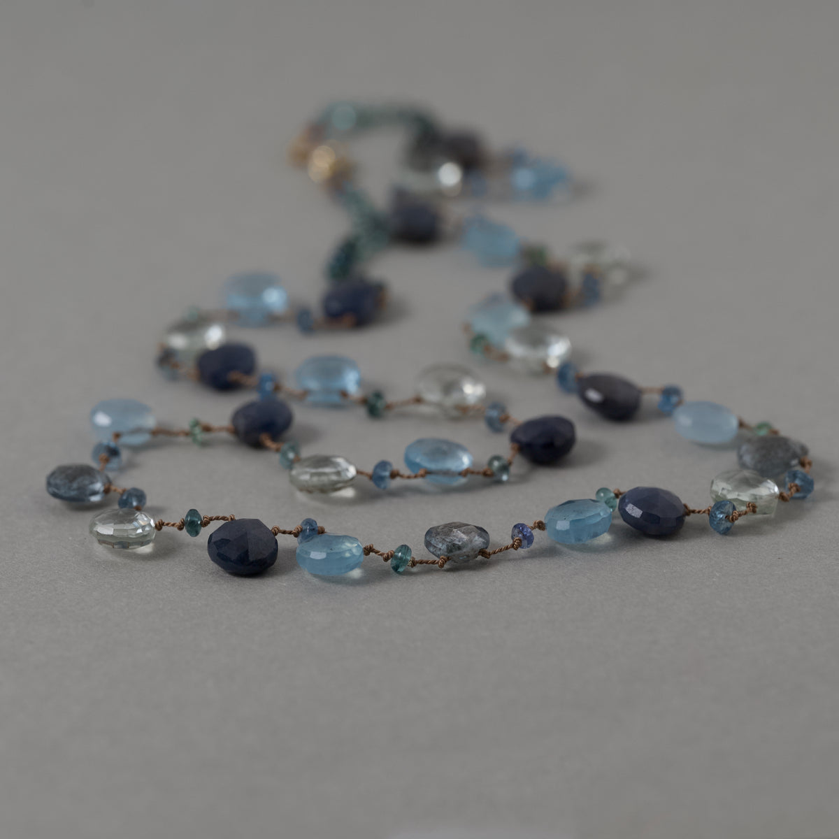 Lido sapphire, aquamarine and tourmaline beads strung on silk with a 14ct gold clasp. 