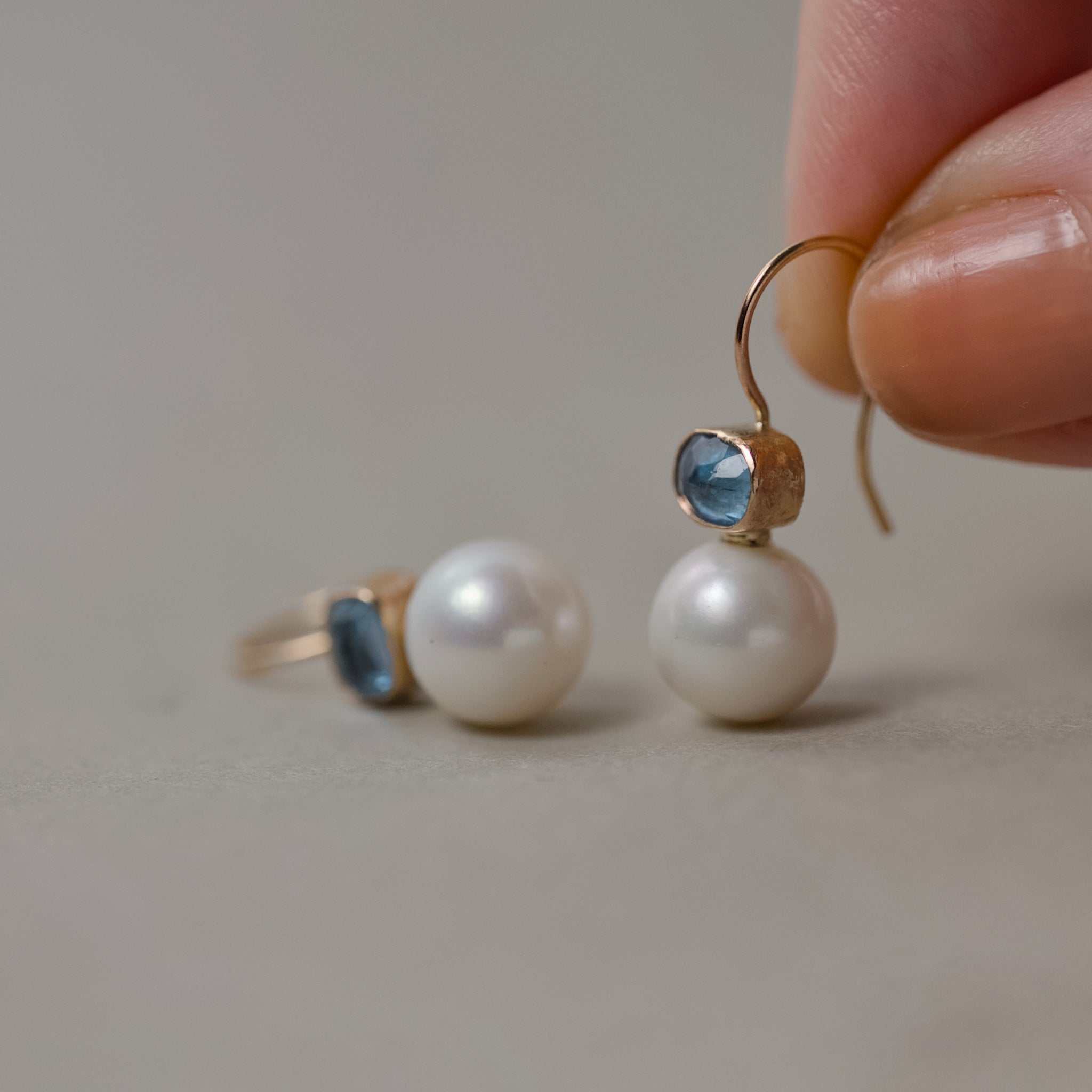aquamarine pearl earrings held in fingers