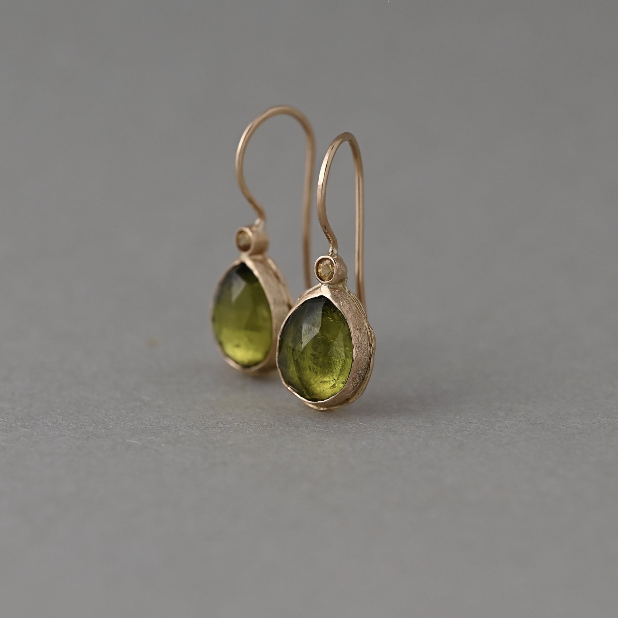 14ct solid gold Pera earrings with natural Arizona peridot pear drops and yellow sapphire accents.