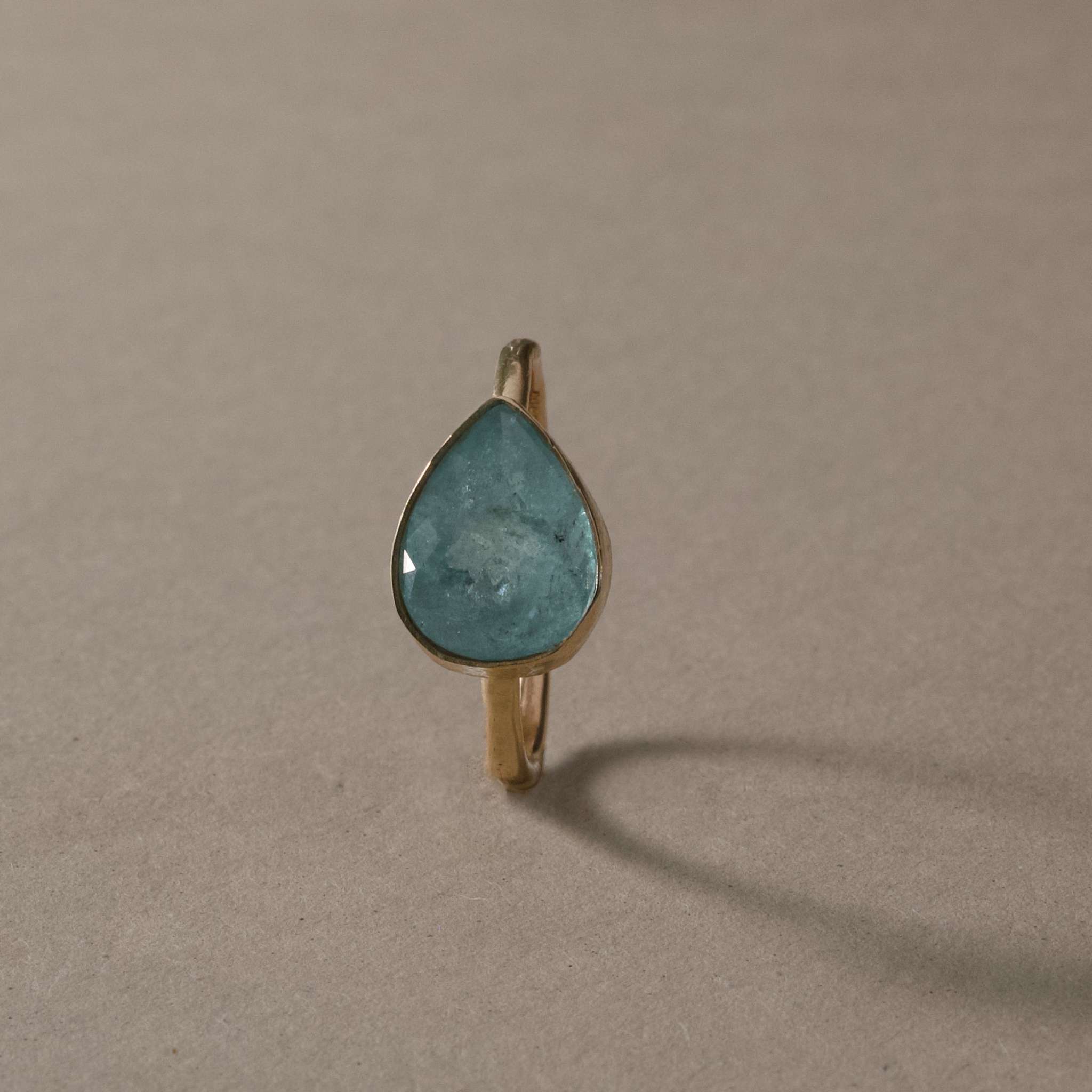 Pero Blue Paraíba Tourmaline Ring with icy aqua gemstone on hammered gold band.