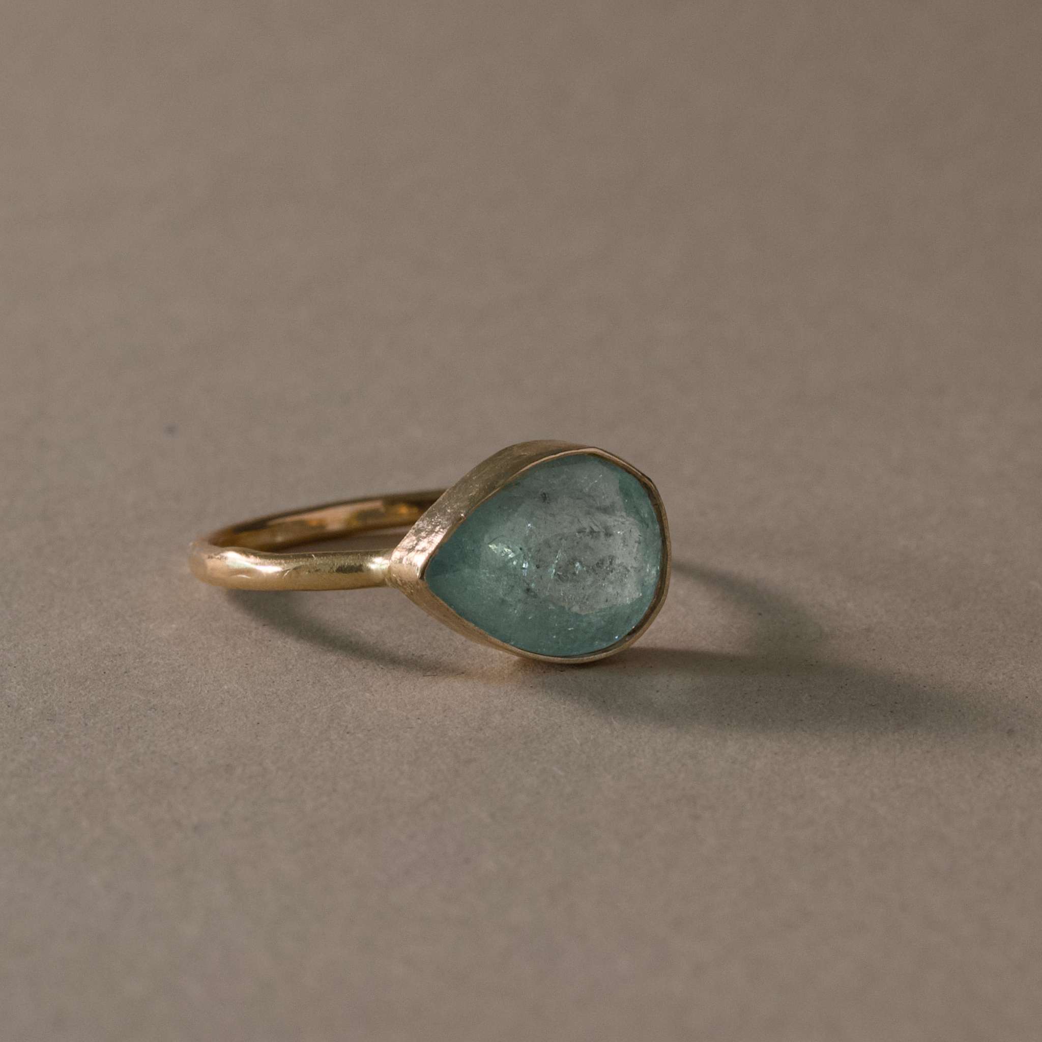 Pero Blue Paraíba Tourmaline Ring with hand-set icy aqua blue gemstone on hammered gold band.