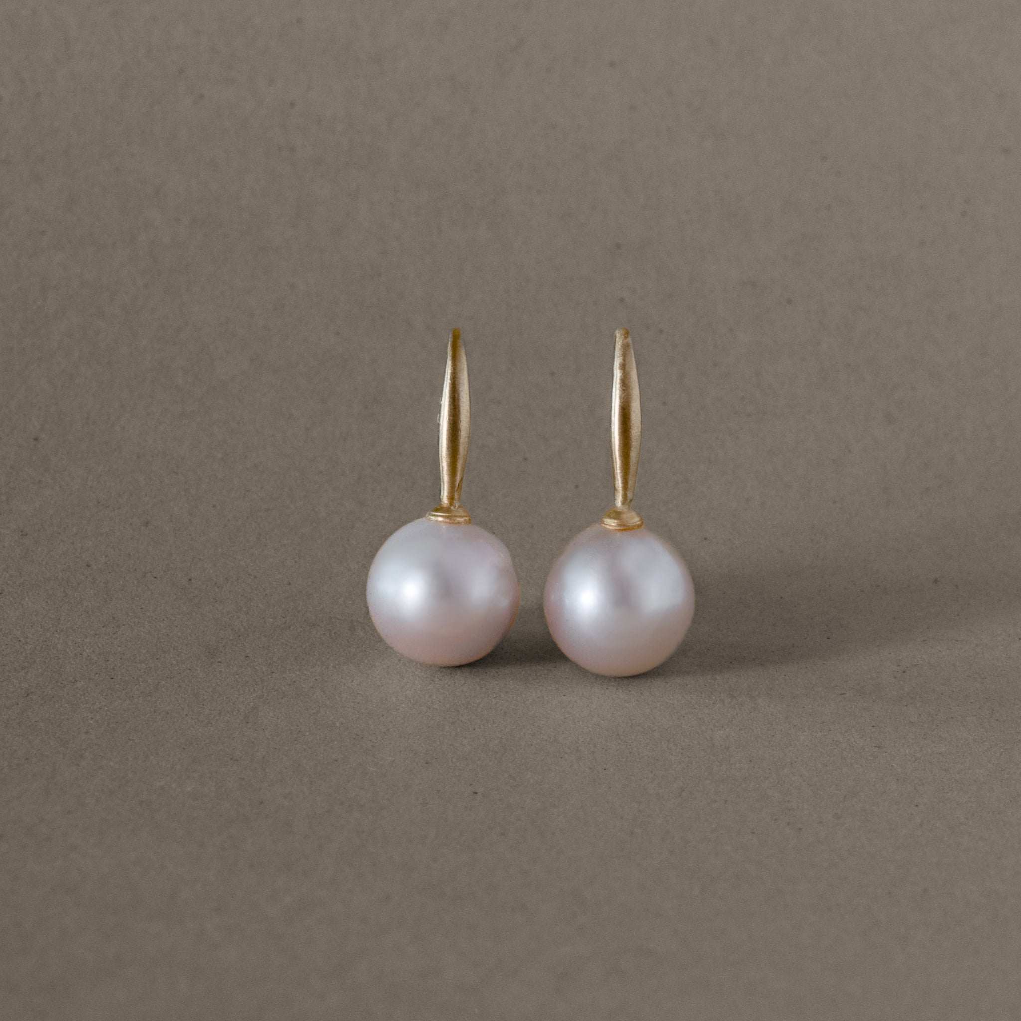 Pink pearl earrings delicately set in gold, showcasing a pale blush hue.