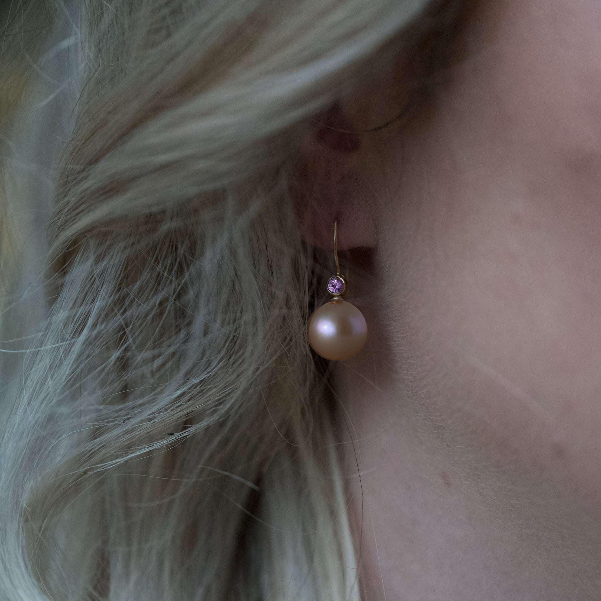 Golden rose freshwater pearl earring with pink sapphire on ear