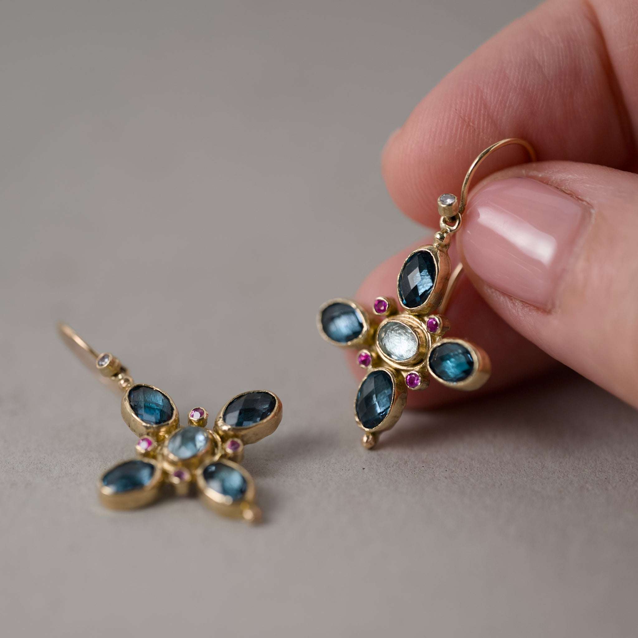 quattro blue topaz aquamarine earrings held in fingers