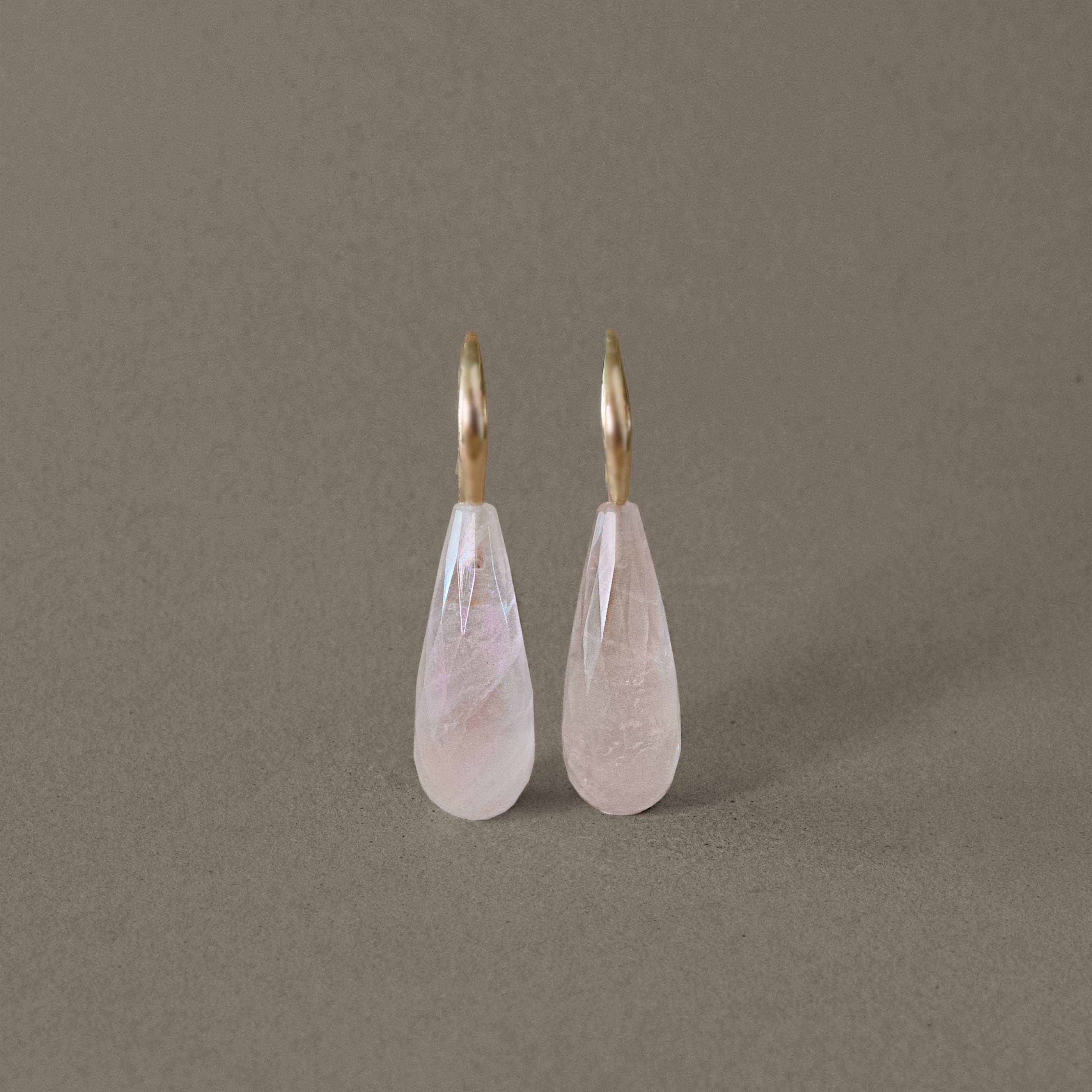 Rose quartz drop earrings with gold hooks on display, highlighting elegant design.