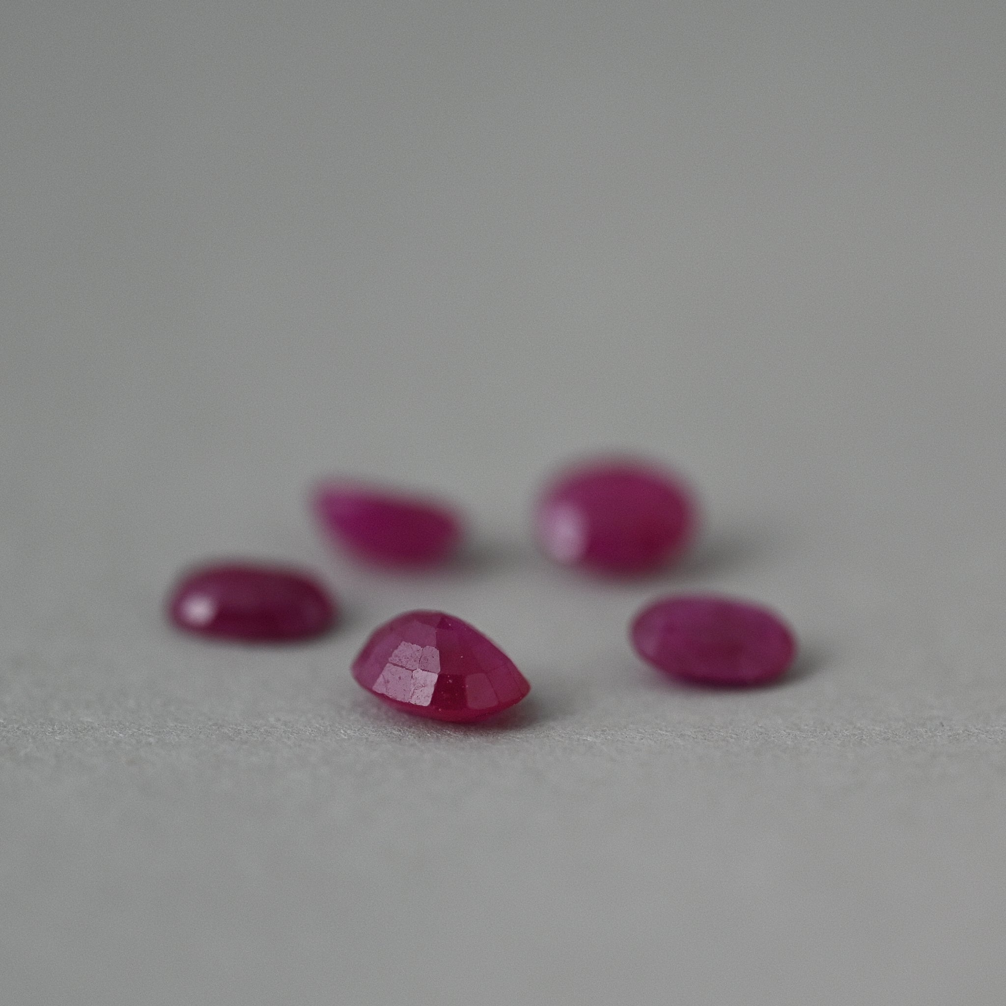 loose Mozambique ruby gemstones on grey paper