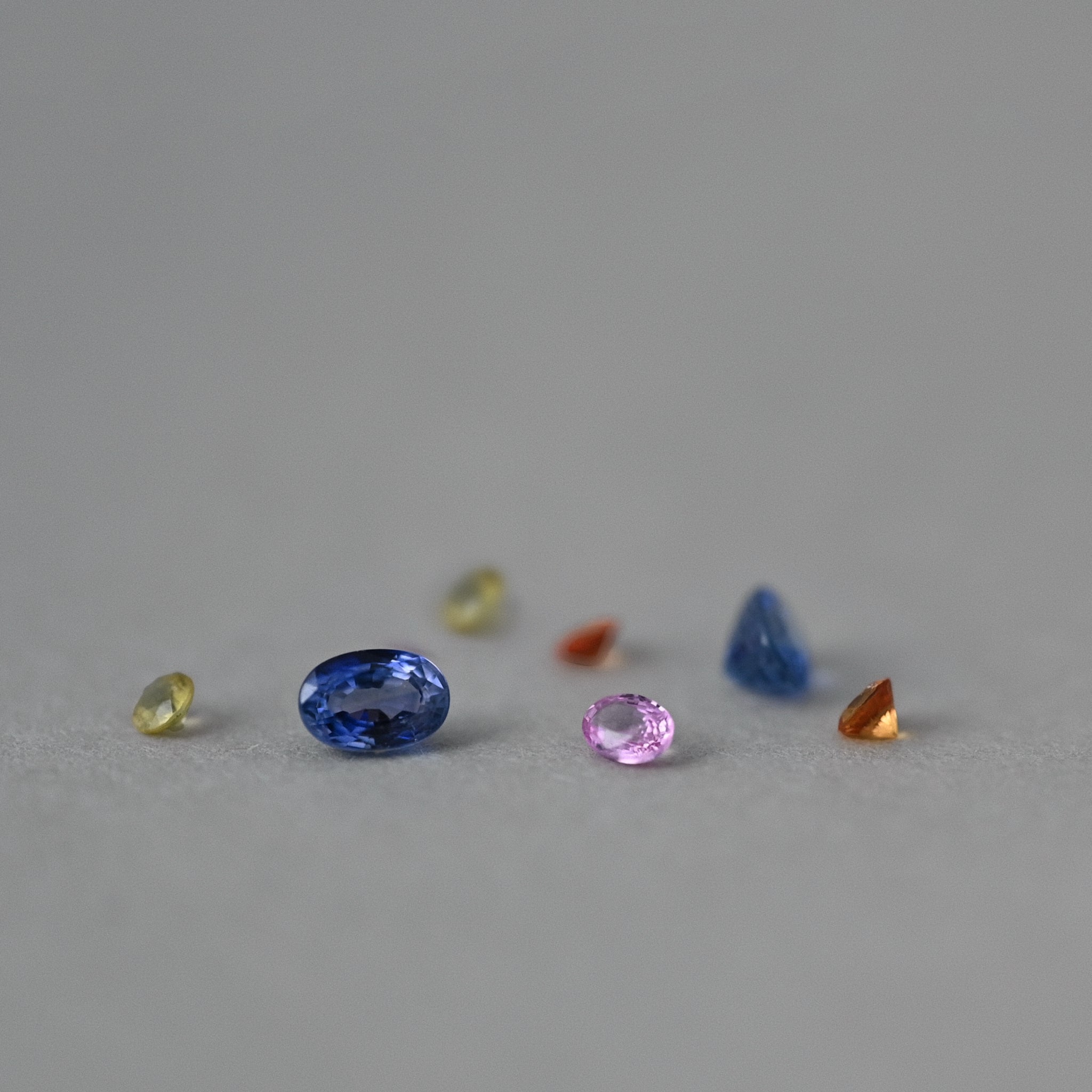 loose mixed sapphire gemstones on grey paper