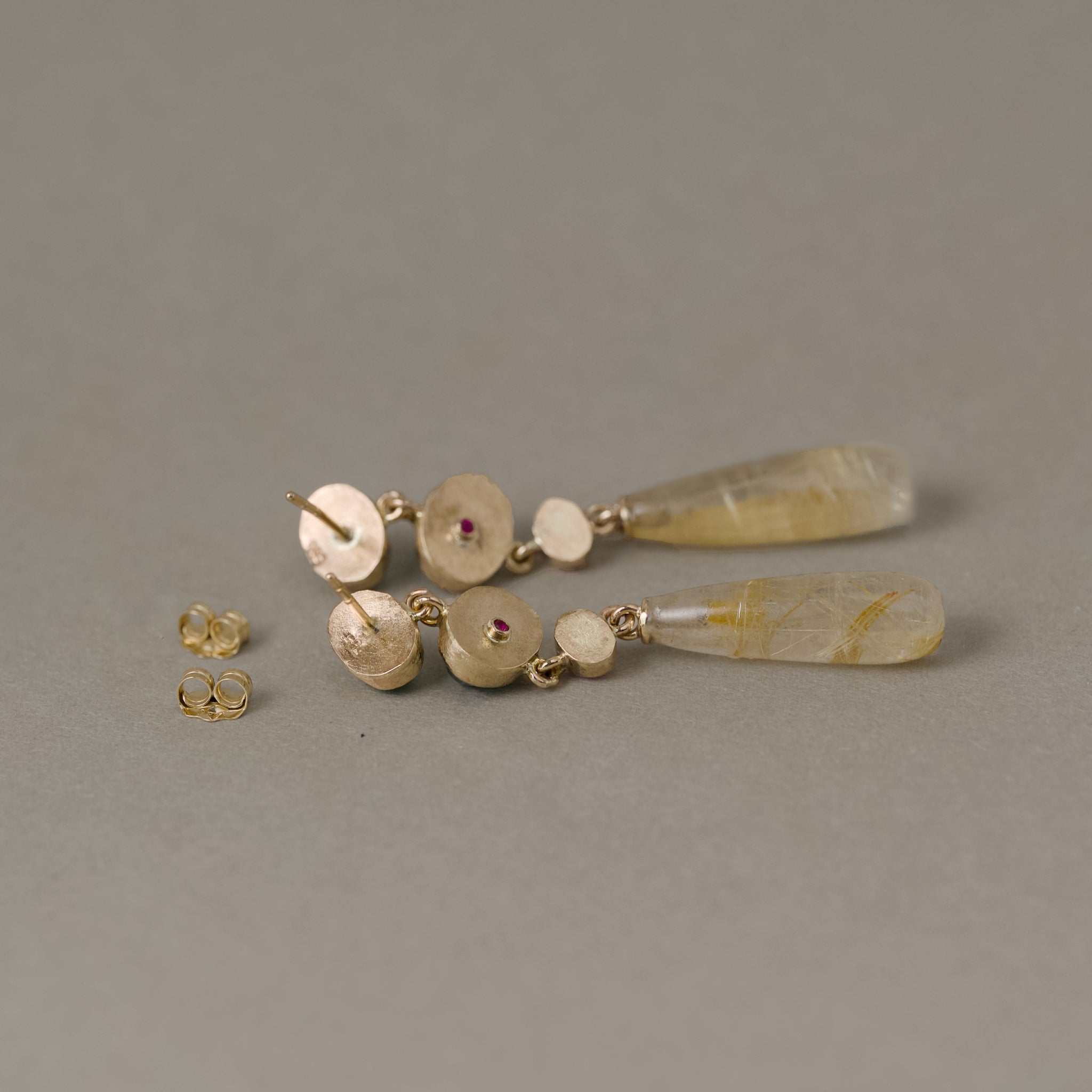 Sera Alta Zambian Emerald Earrings with d rose sapphires and gold rutilated quartz in 14ct gold setting showing backs with ruby accent