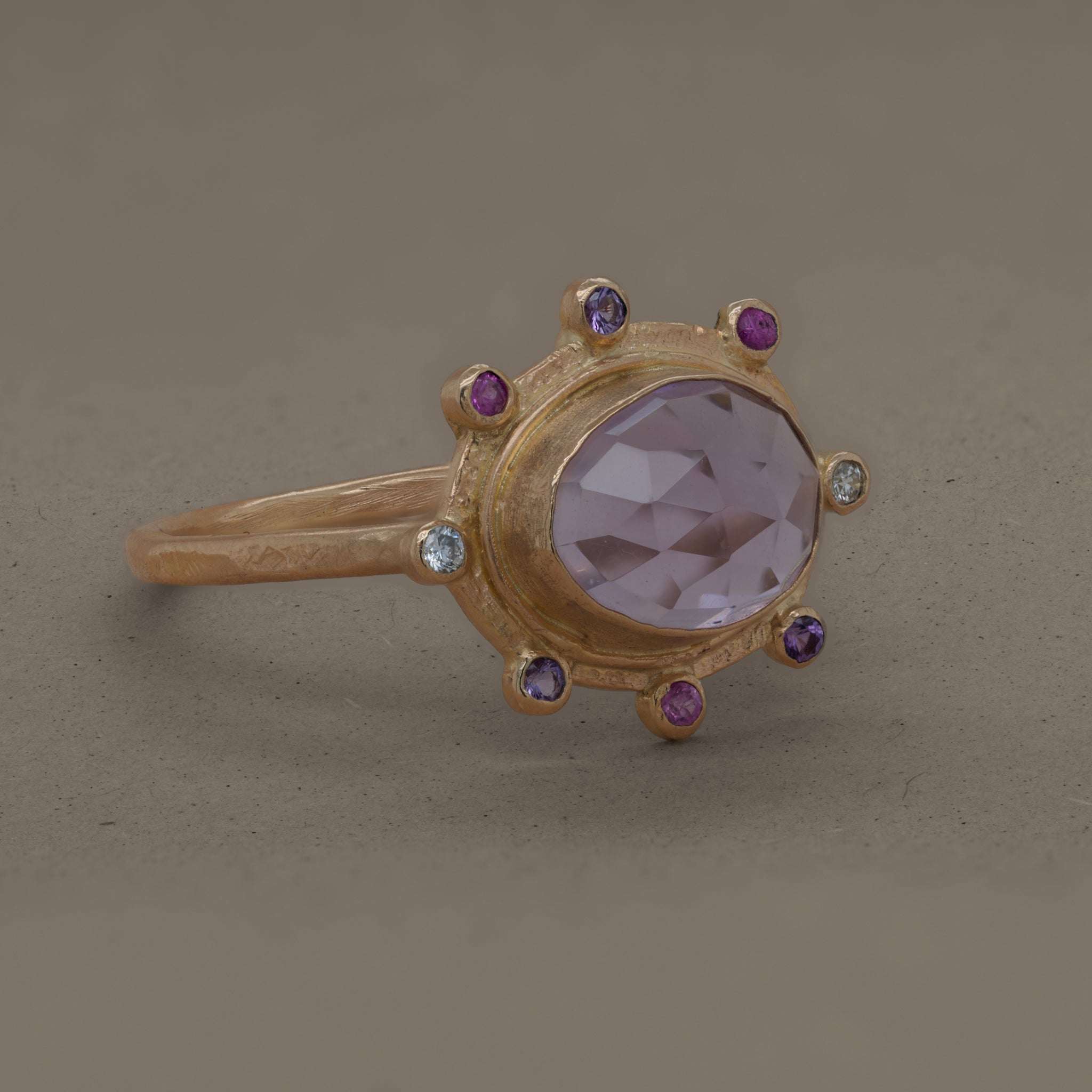 Amethyst ring with lilac gemstone, gold setting, accented by sapphires and diamonds.