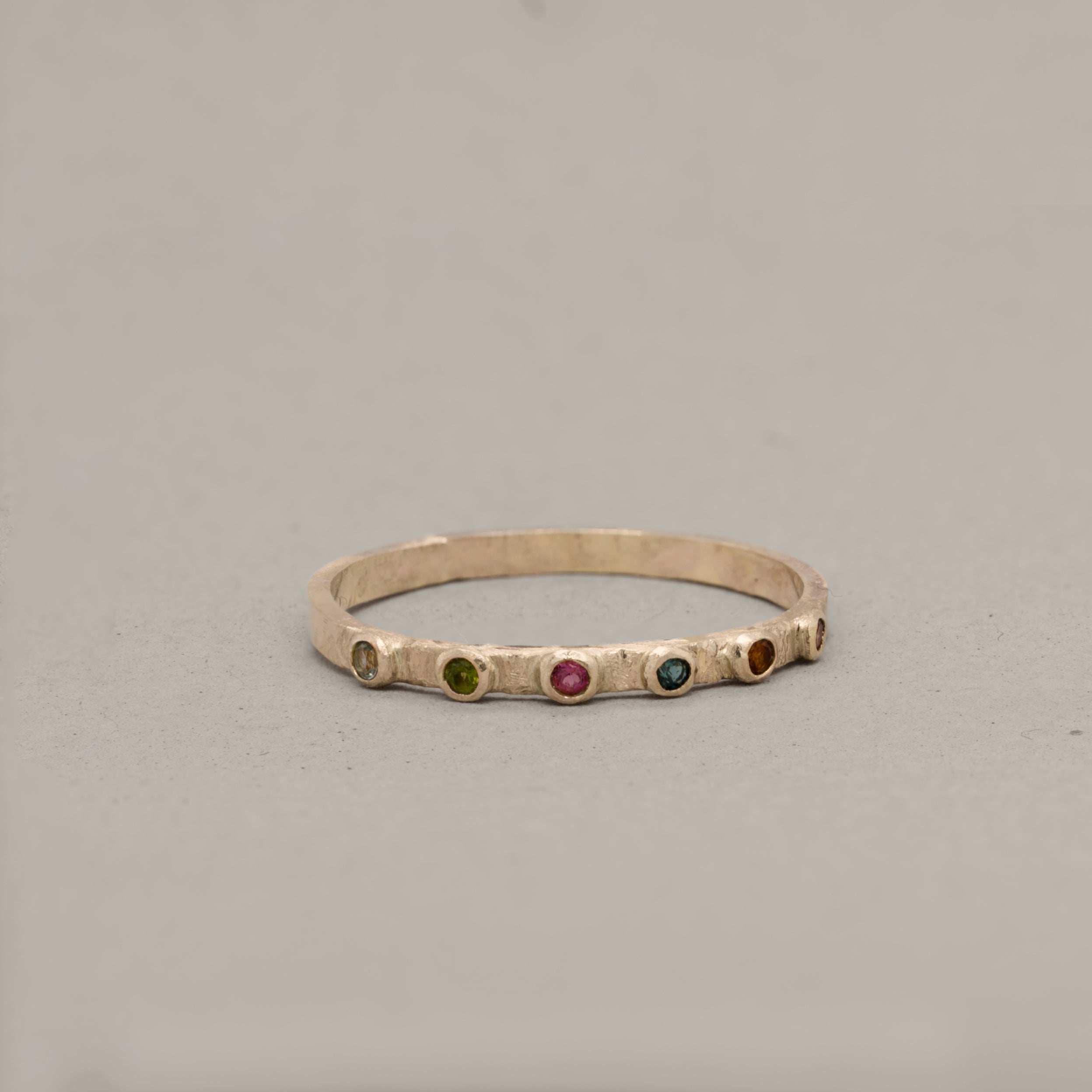 Stellata Tourmaline Ring with textured gold band and multicolored tourmaline stones in a delicate design
