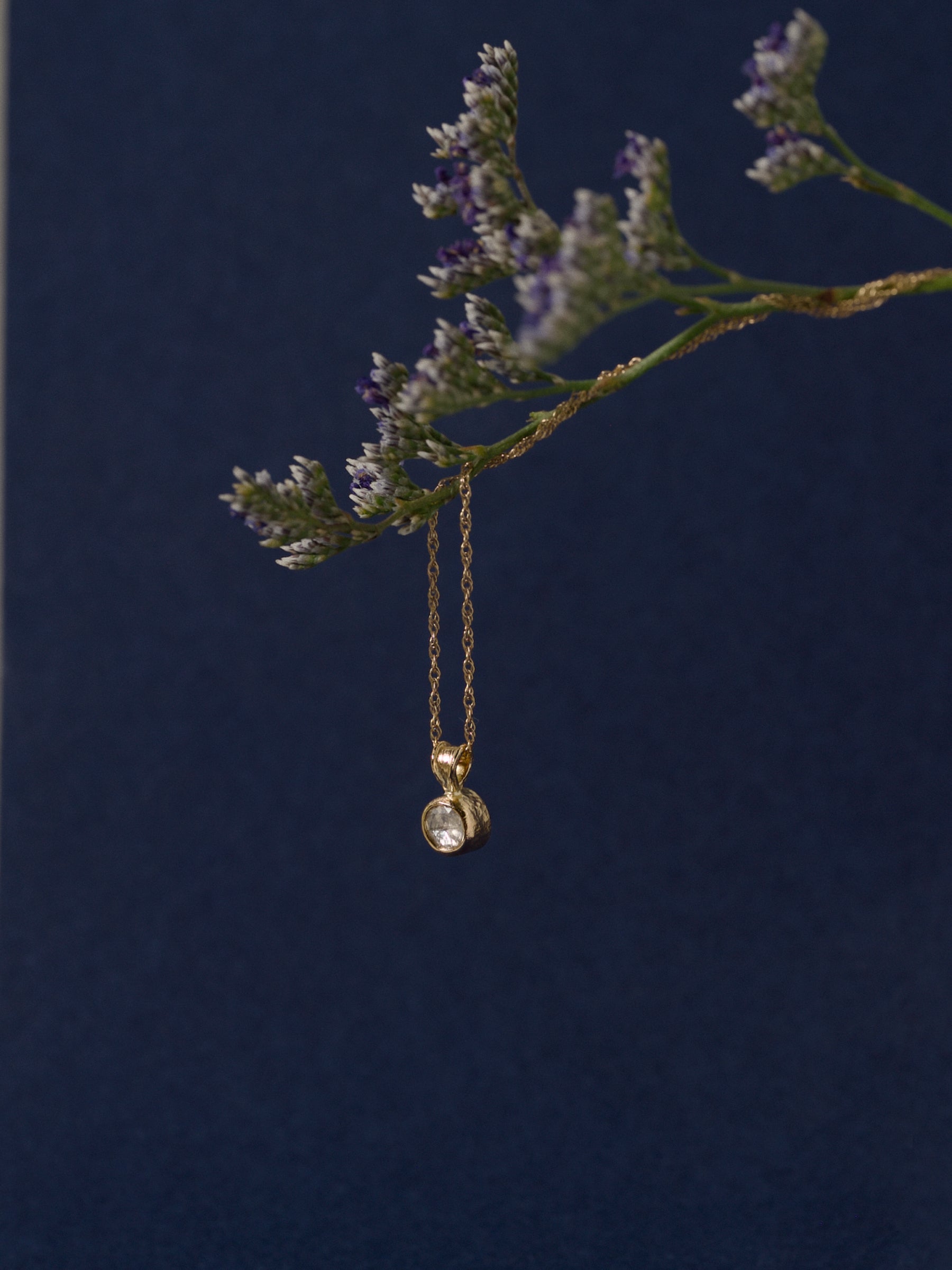 Rose cut diamond pendant in 14ct gold on fine chain against deep blue background